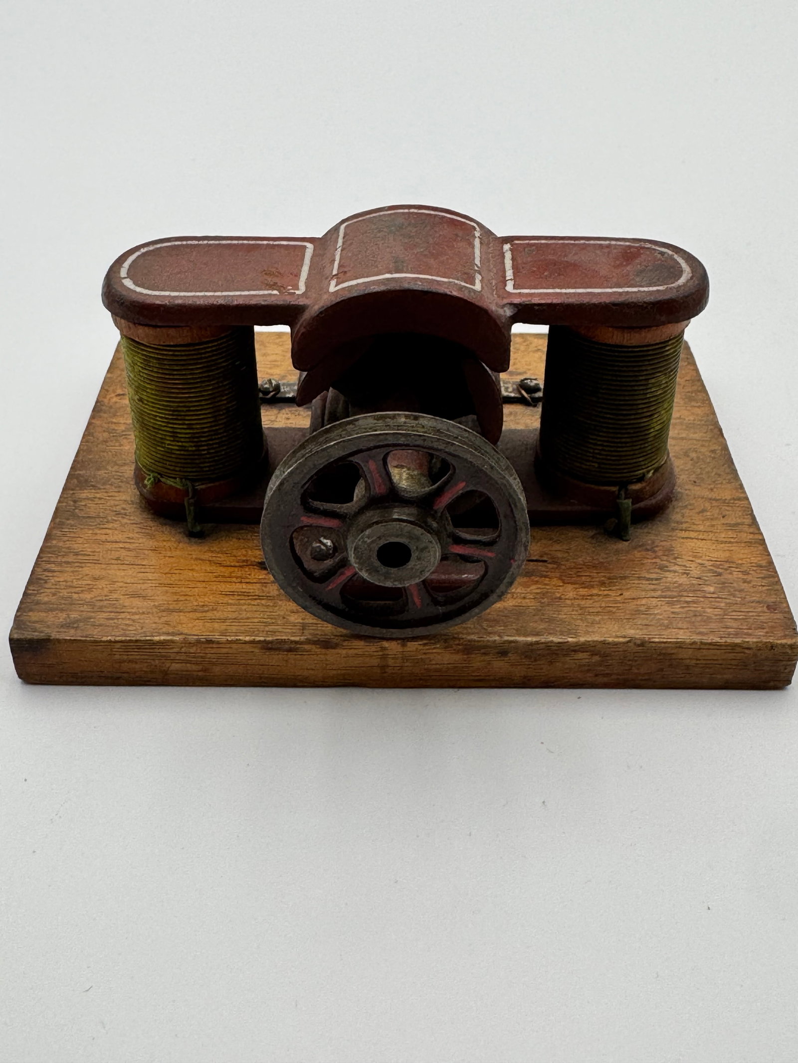 Antique Early Electric Motor Scientific Demonstration Model Wood Base Electromagnet: Antique early electrical demonstration motor mounted on original wood base. Features dual electromagnet coils, cast iron flywheel, and original red painted finish with hand-painted pinstripe details. 