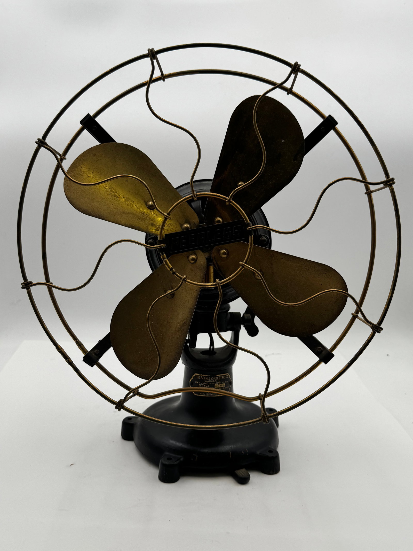 Antique Peerless Brass Blade Electric Fan Warren Ohio 110V: Beautiful early Peerless Electric Co. desk fan featuring four original brass blades, decorative S-wire cage, and heavy cast iron motor housing and base. Front badge retains the embossed “PEERLESS&rd