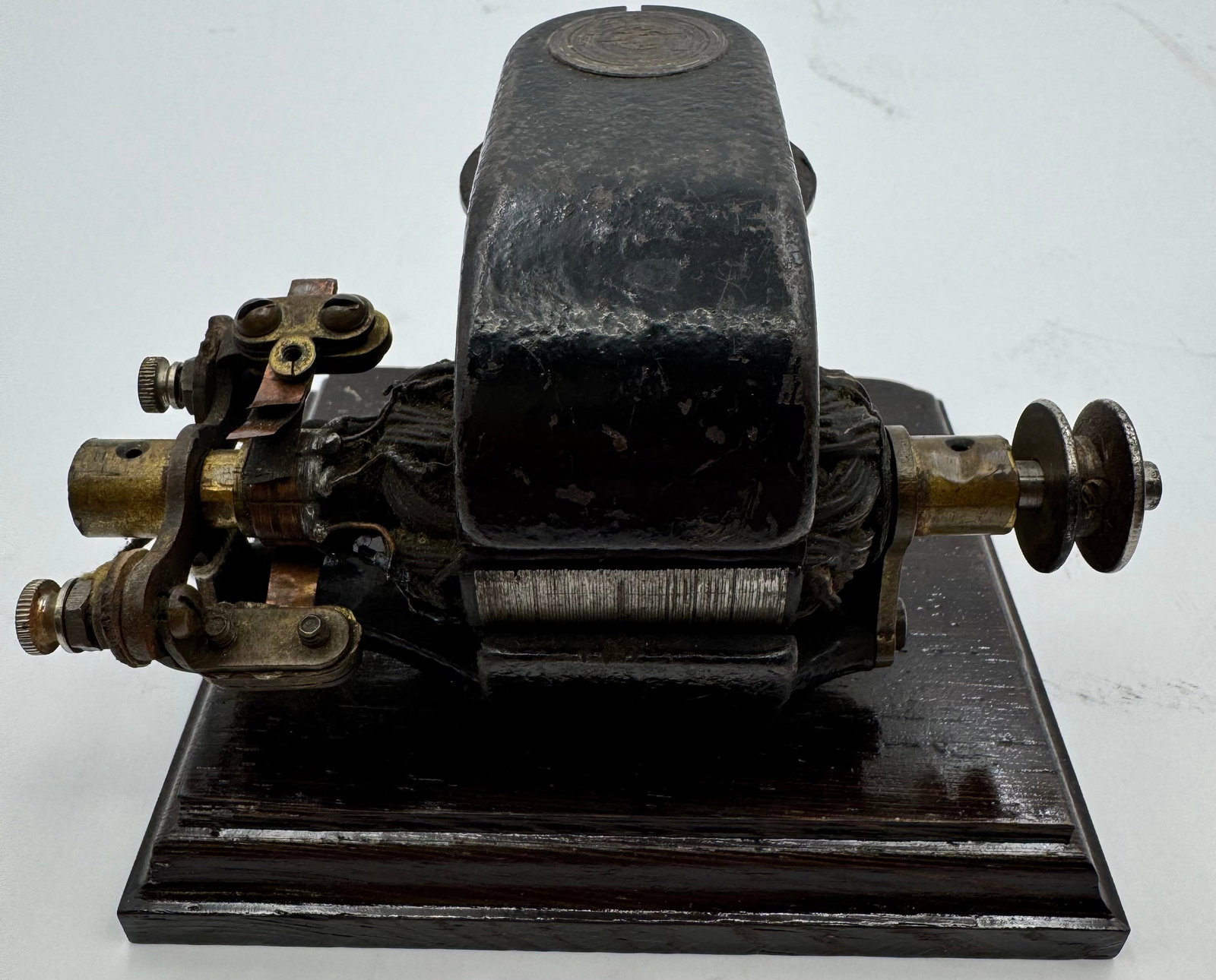 Antique Electric Telegraph Sounder Motor on Wood Base: Antique early electrical apparatus or telegraph sounder/motor mounted on a wooden display base. Features exposed copper contacts, wound coils, pulley wheel, and cast metal housing with original aged f