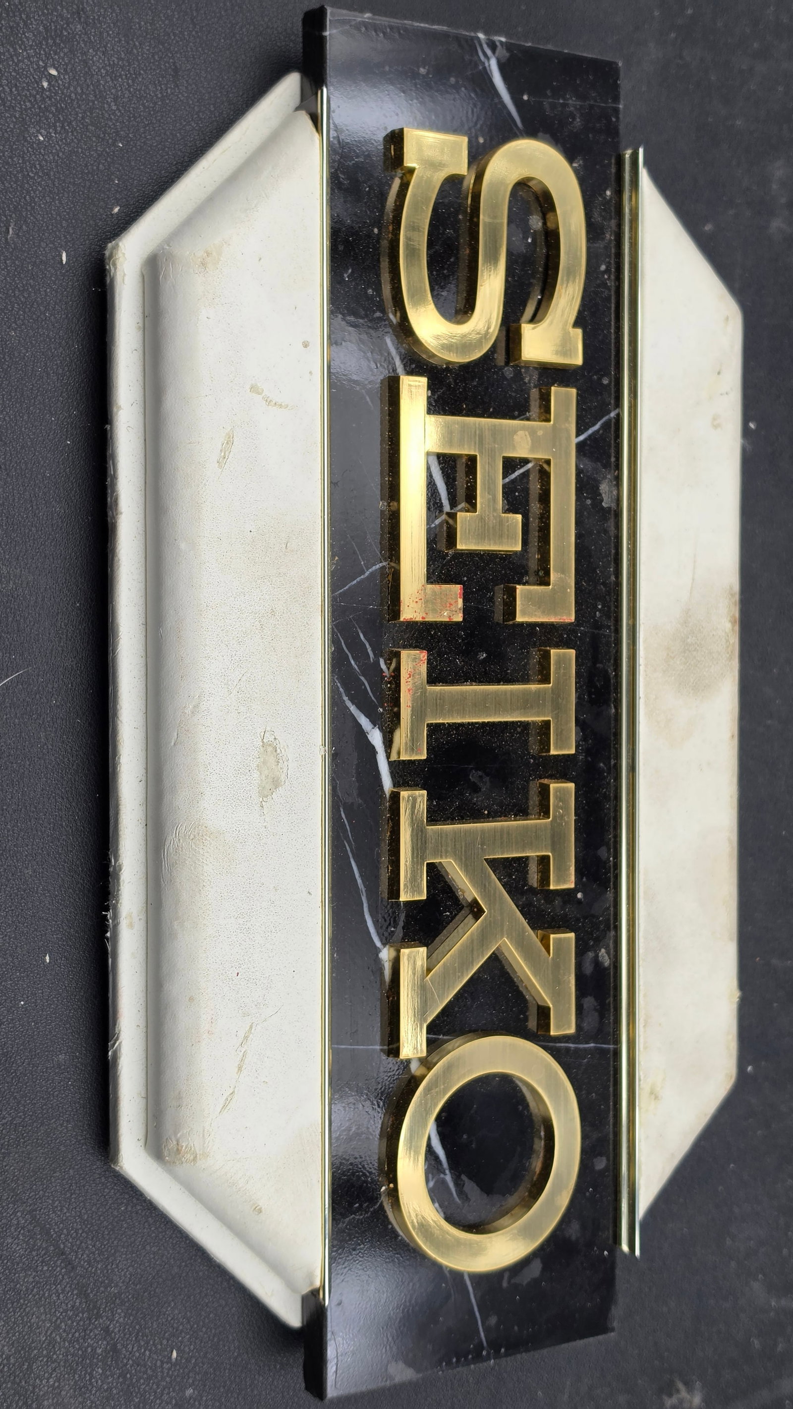 Vintage Seiko Authorized Dealer Display Sign Brass Letters Marble Look Panel 1980s 11": This is an original Seiko authorized dealer point-of-sale display sign from the 1980s, measuring approximately 11 inches in length. The face consists of a rectangular black marble-look acrylic panel f