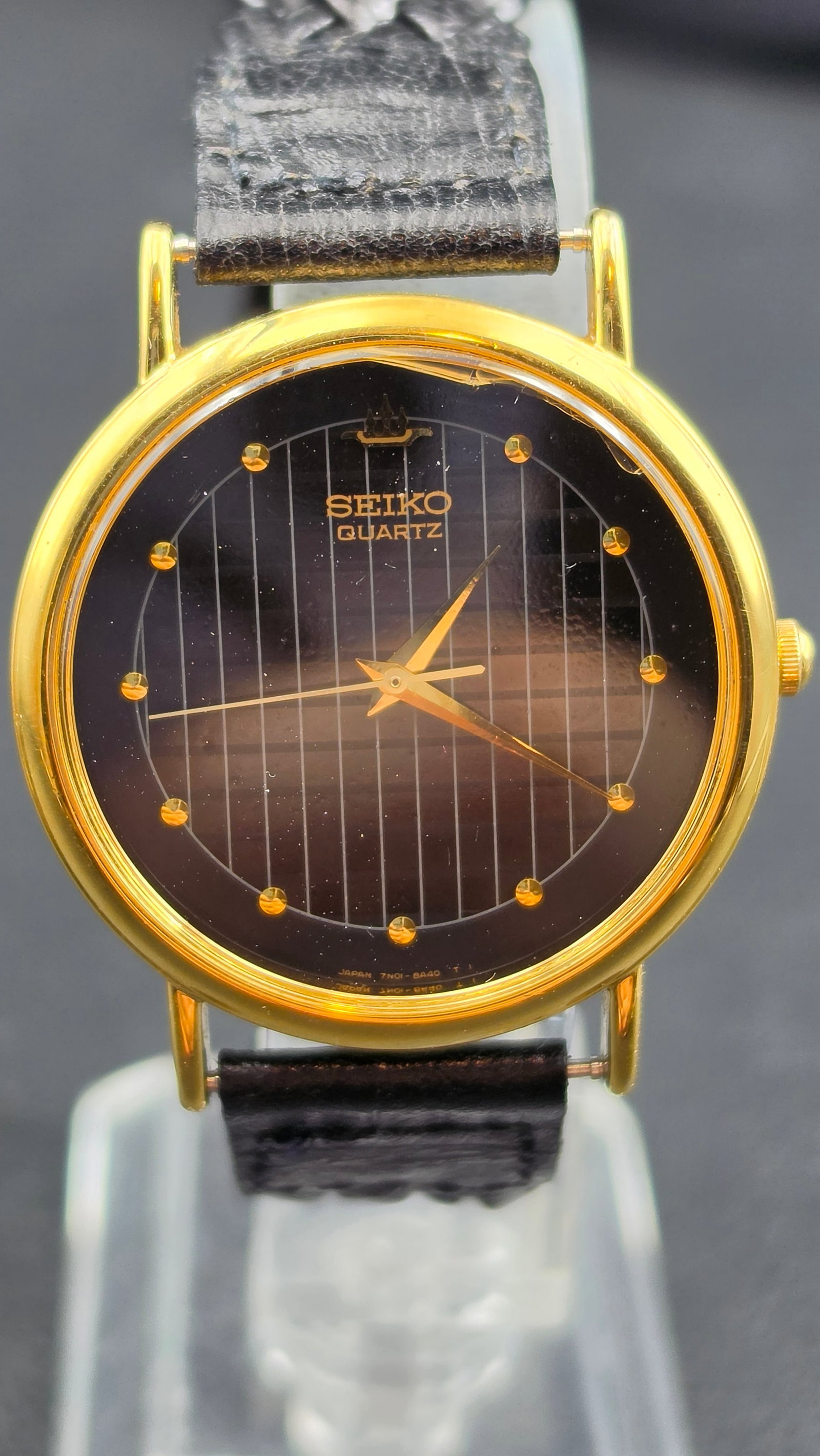 Seiko Quartz Dress Watch Gold Tone Dark Pinstripe Dial Cal. 7N01-8A10 Japan c. 1990s: This is a vintage Seiko quartz dress watch powered by caliber 7N01, reference 7N01-8A10, produced in Japan in the early 1990s. The case back is stamped Seiko, Base Metal, St. Steel Back, confirming a 