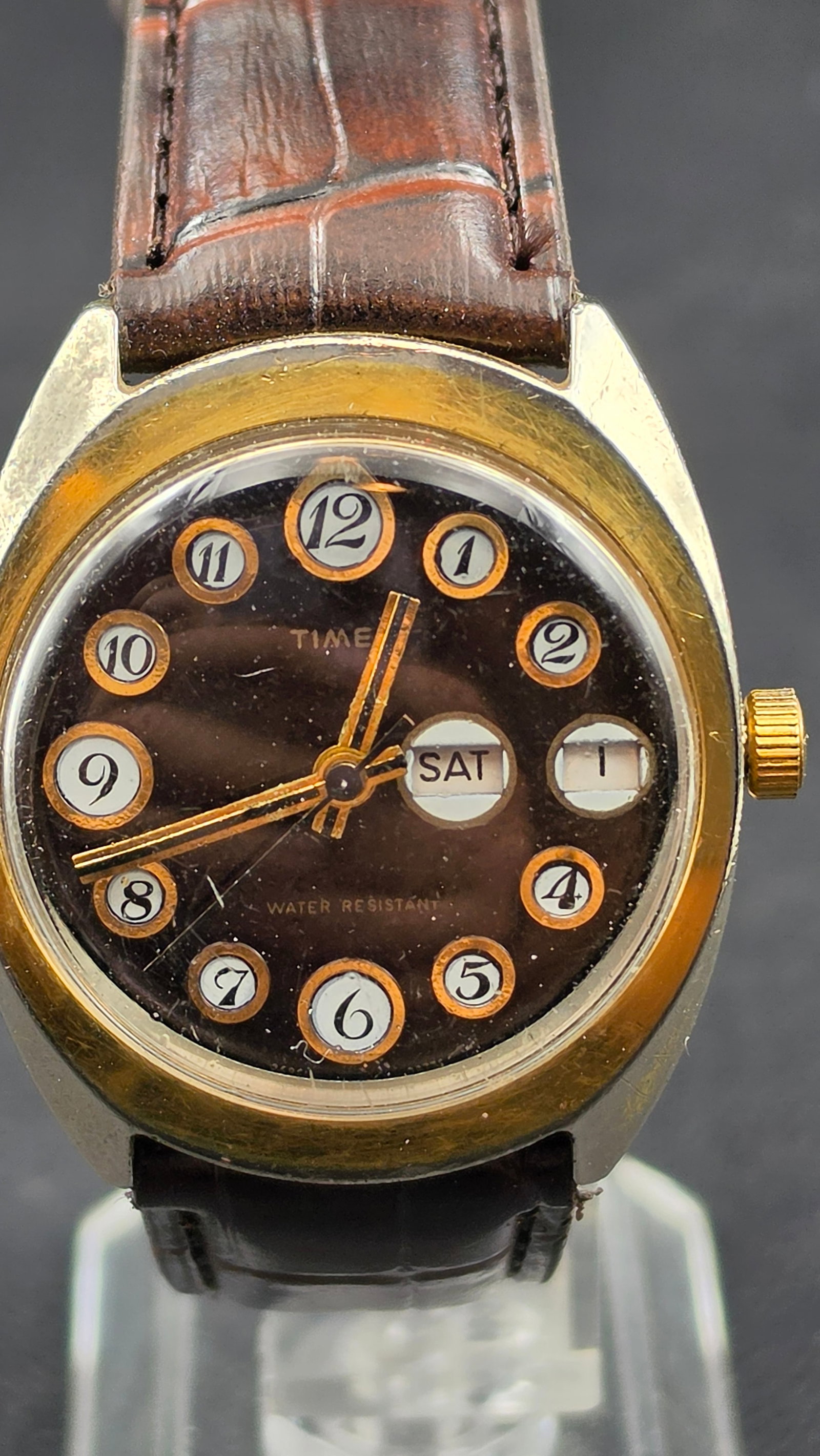 1970s Timex Men's Day-Date Watch Dark Brown Bubble Numeral Dial Gold Tone: This is a vintage 1970s Timex men's day-date wristwatch featuring one of the brand's more visually distinctive dial designs of the era — a rich dark brown dial with bold Arabic numerals set inside i