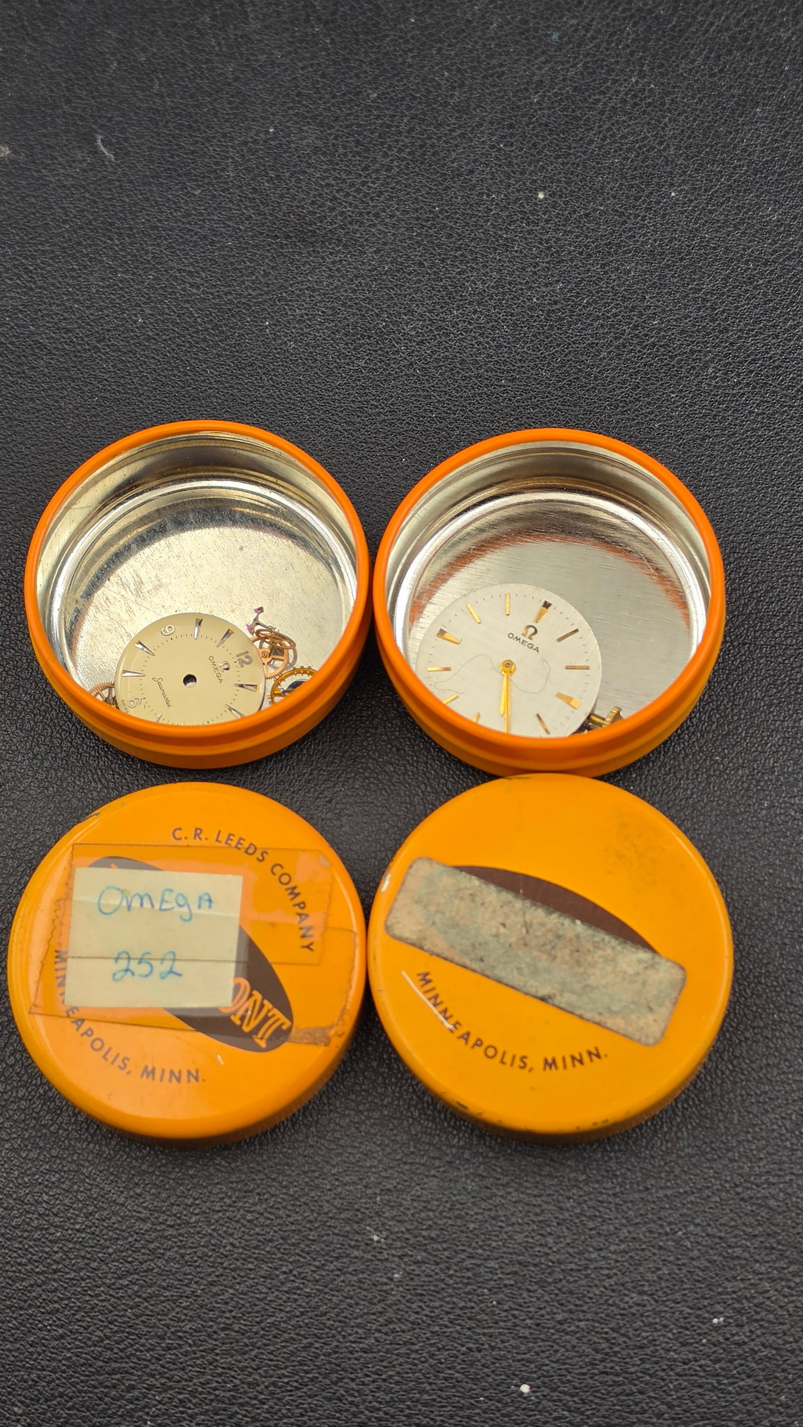 Lot 2 Omega Swiss Watch Movement & Dial Assemblies Cal 920 Seamaster + Baton Dial in C.R. Leeds Tins: This is a lot of two vintage Omega Swiss watch movement and dial assemblies presented in their original C.R. Leeds Company watchmaker storage tins from Minneapolis, Minnesota — a provenance detail t