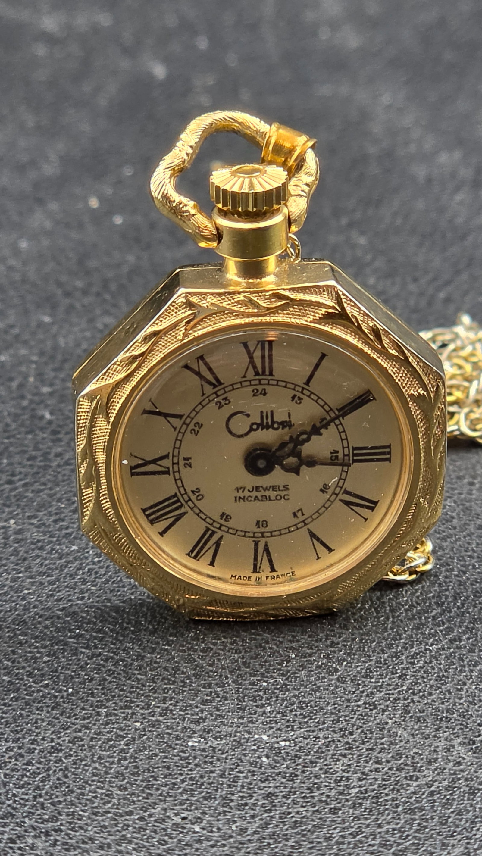 c.1970s Colibri 17 Jewels Incabloc Made in France Octagonal Pendant Watch Necklace 24.92mm Gold Tone: This is a charming vintage French-made ladies pendant watch by Colibri, produced in France and housed in a gold-tone base metal octagonal case measuring approximately 24.92mm across. The case back pap