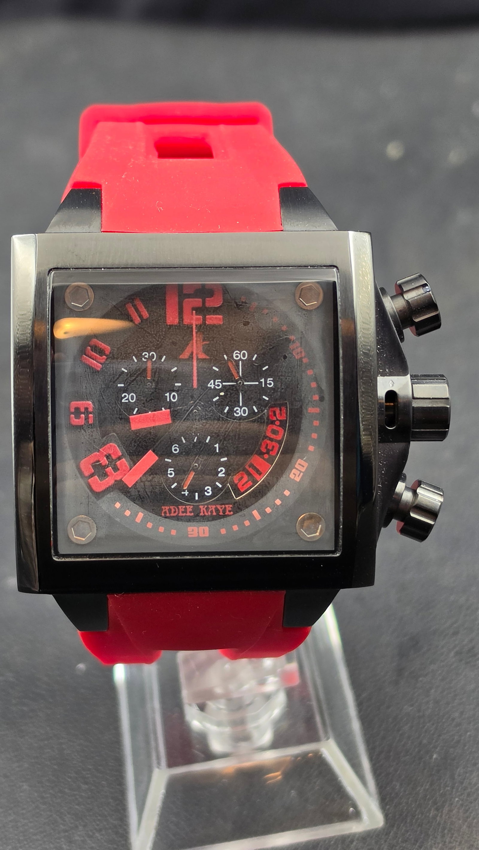 Adee Kaye AK7115-M Swiss Parts Chronograph 40mm Square Black PVD Red Dial Rubber Strap Men's Watch 2: Up for sale is an Adee Kaye square-case chronograph, Model AK7115-M, No. 0573, in a bold black PVD stainless steel case with a striking red and black colorway. Adee Kaye is a Beverly Hills-based brand