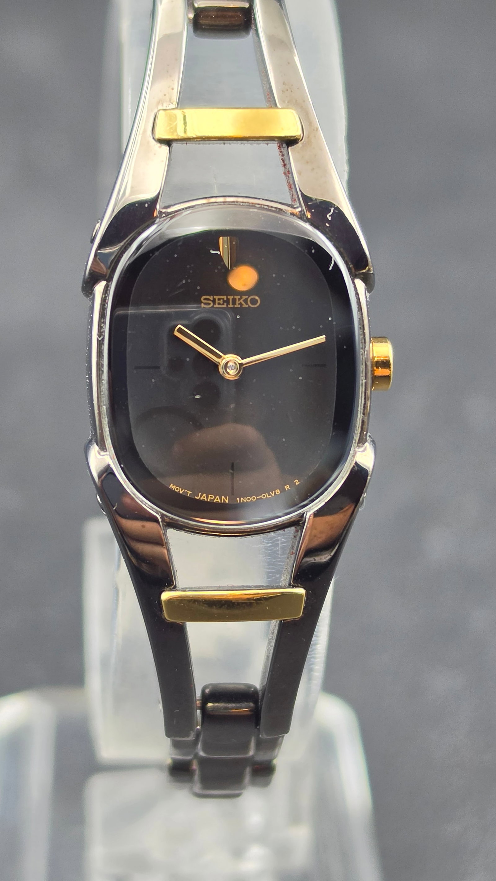 Seiko Ladies Two-Tone Black Dial Dress Watch 1N00-0HG0 18mm Stainless Steel Bracelet Running: This is a Seiko ladies quartz dress watch, reference 1N00-0HG0, running the caliber 1N00 quartz movement with Japan movement designation. The cushion-oval stainless steel case measures 18.01mm wide in
