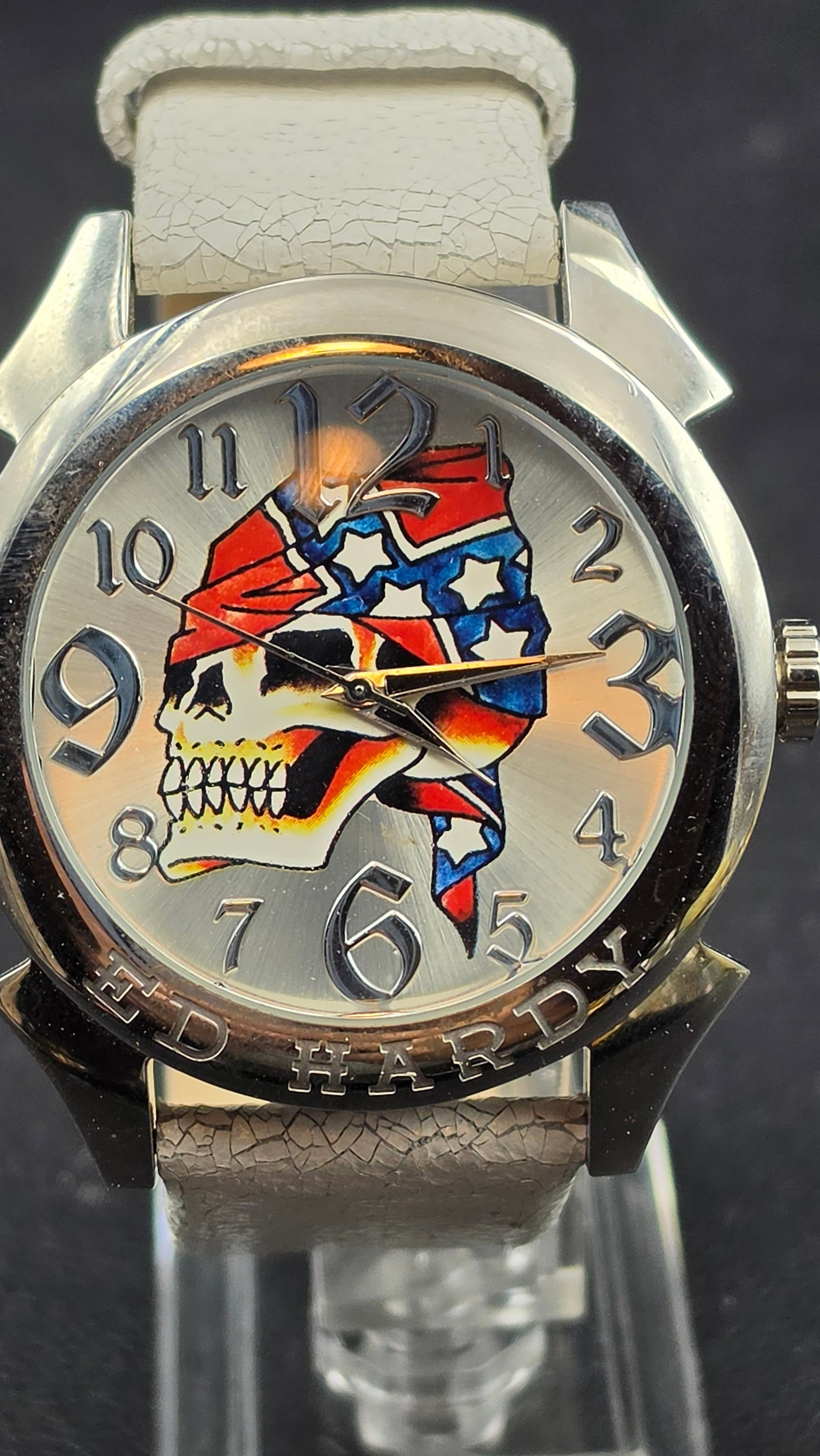 Ed Hardy EV-SK0120 Skull Flag Graphic Dial Quartz Watch White Crackle Strap 2000s: This is an Ed Hardy quartz watch from the 2000s, ref. EV-SK0120, running on a Japan movement. The watch features a bold full-color illustrated dial depicting a skull wearing a Confederate-flag bandana