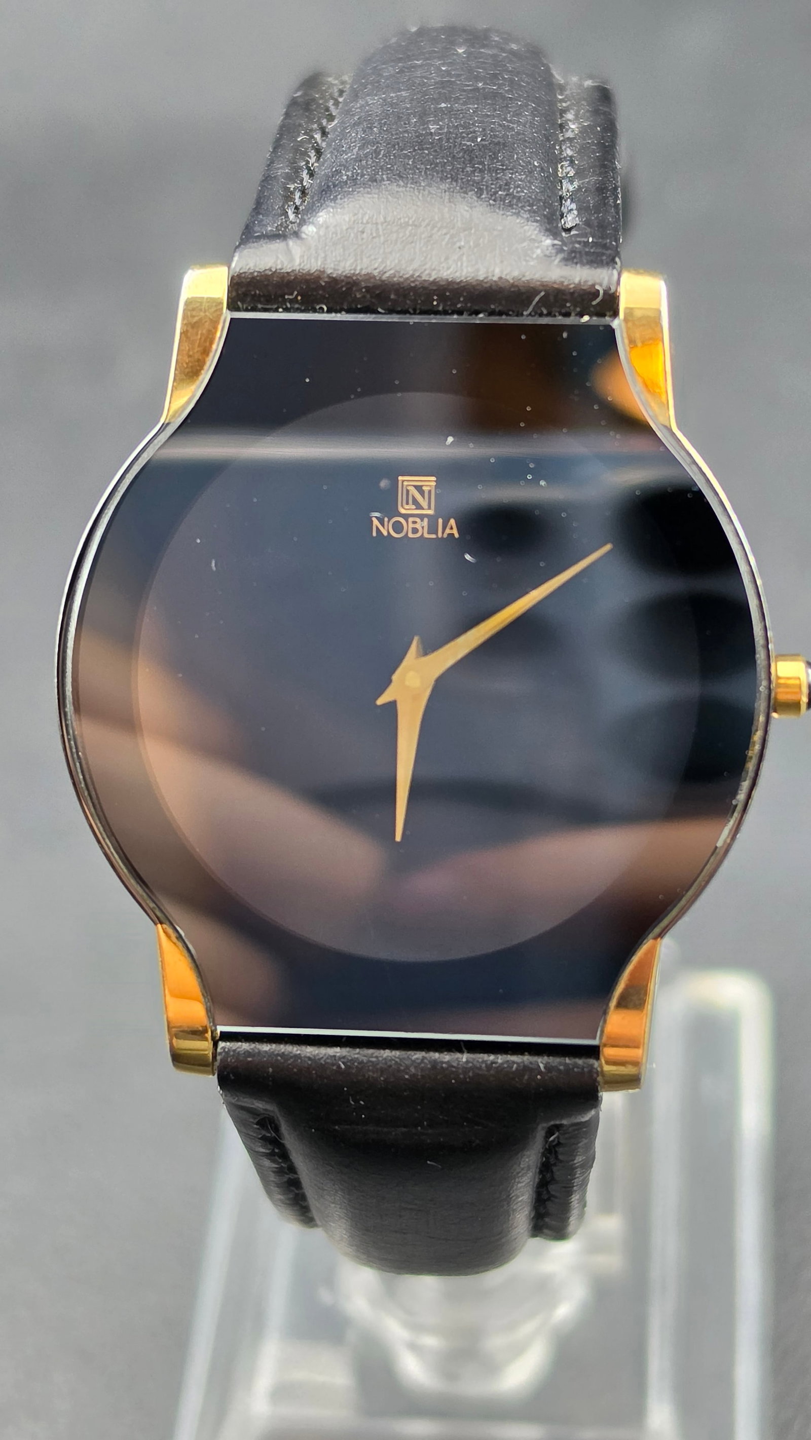 Vintage 1980s Noblia Ultra-Thin Black Mirror Dial Gold-Tone Quartz Watch No. 3070141 33mm: This is a sleek and minimalist vintage Noblia dress watch, serial 3070141, measuring approximately 33.21mm across the two-tone case with gold-tone lugs and bezel against a polished steel mid-case. The