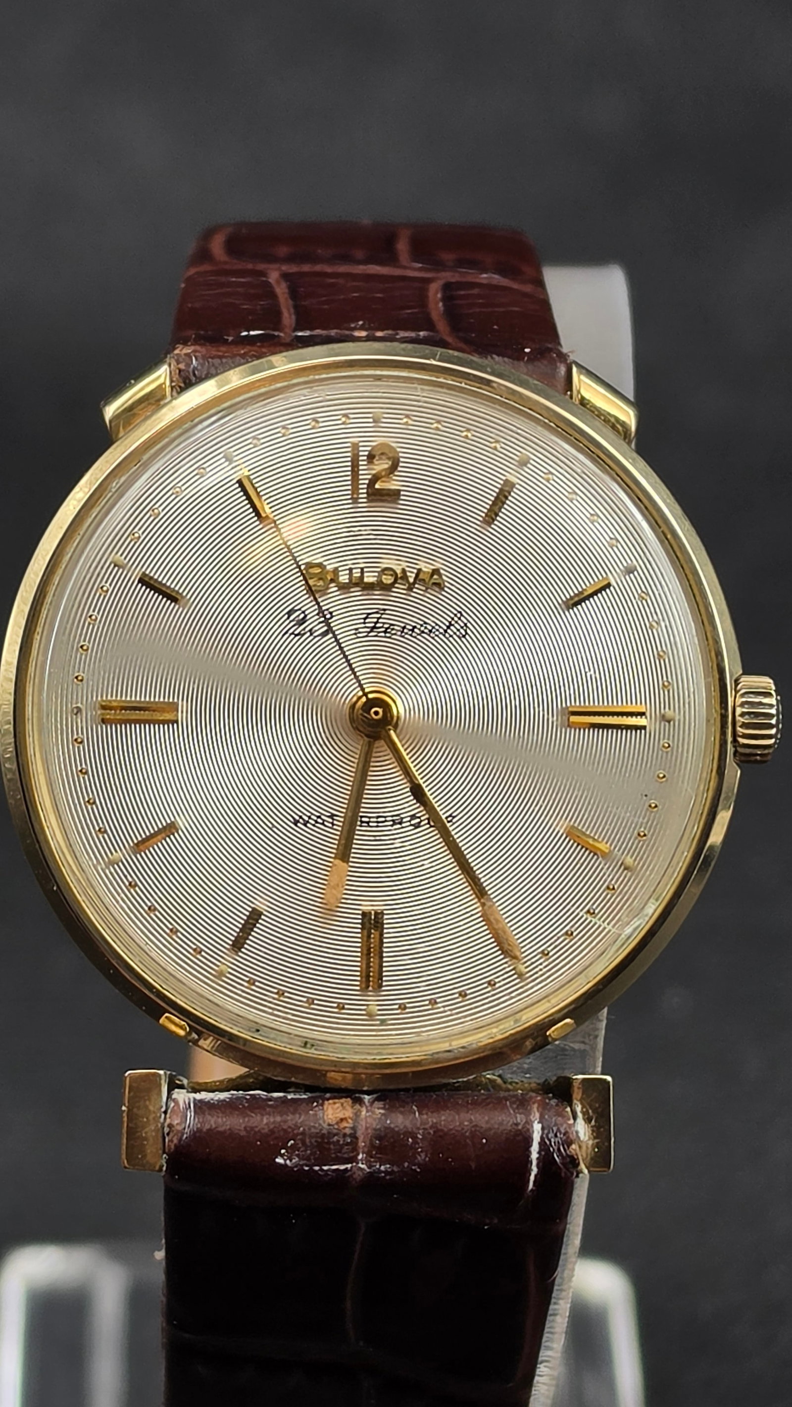 Bulova 23 Jewel 10BZC Caliber 10K Gold Filled Guilloche Dial Men's Watch 32mm, 1960, Running: This is a near-mint Bulova dress watch, case serial E709694, dating to 1960 per Bulova's date code system (E = 1960s decade, 0 = year zero of that decade, confirmed by the "E" prefix and serial range)
