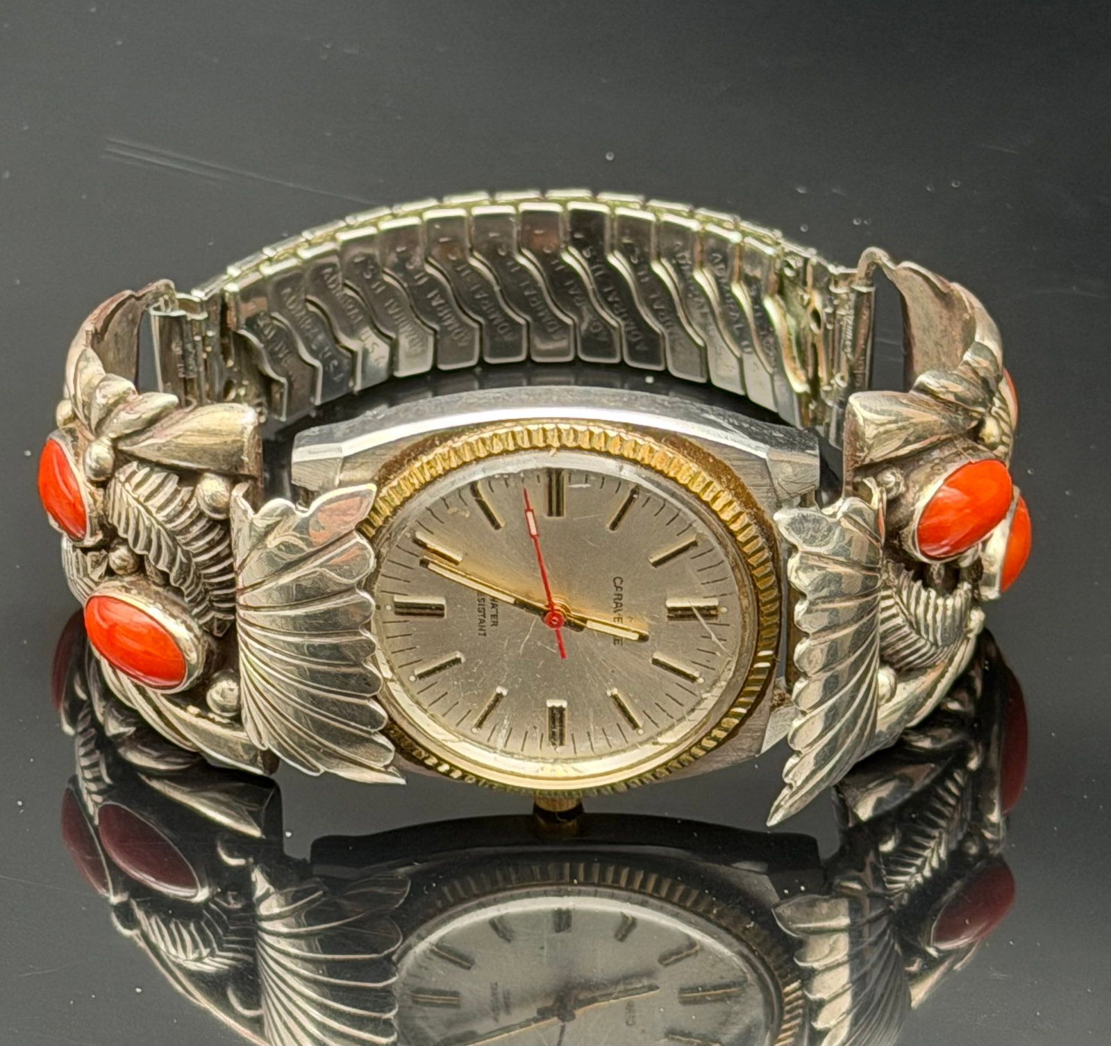 103g-Adam Pallin Native American Sterling Silver Coral Watch Bracelet Caravelle Watch Signed MF Cara: Vintage Native American watch bracelet by Adam Pallin featuring handcrafted sterling silver overlays accented with vibrant red coral cabochons. The bracelet incorporates traditional Southwestern feath