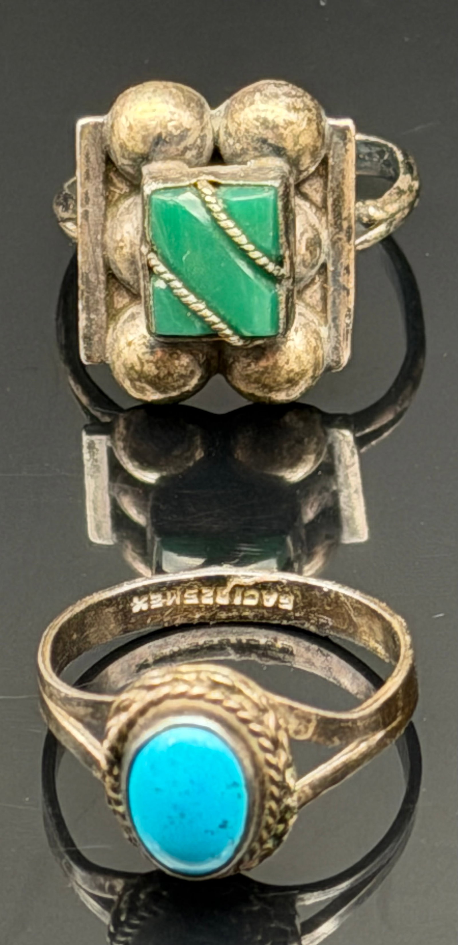 7g-Title Vintage Mexico Sterling Silver Turquoise & Green Stone Ring: Pair of vintage Mexican sterling silver rings featuring Southwest-inspired designs. One ring showcases an oval turquoise cabochon in a rope-twist bezel setting, while the other features a geometric sq