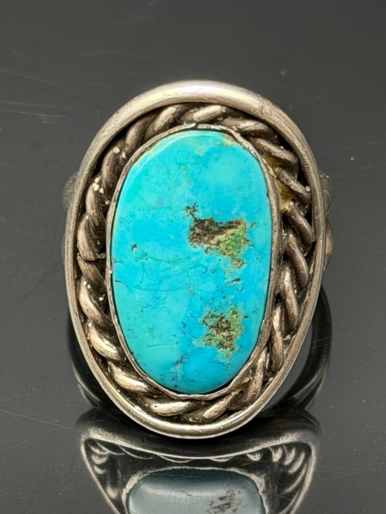 17g-Vintage Sterling Silver Turquoise Statement Ring: Vintage sterling silver ring featuring a large natural turquoise cabochon set within a twisted rope border. The ring showcases classic Southwestern styling with a substantial split-shank band and vibr