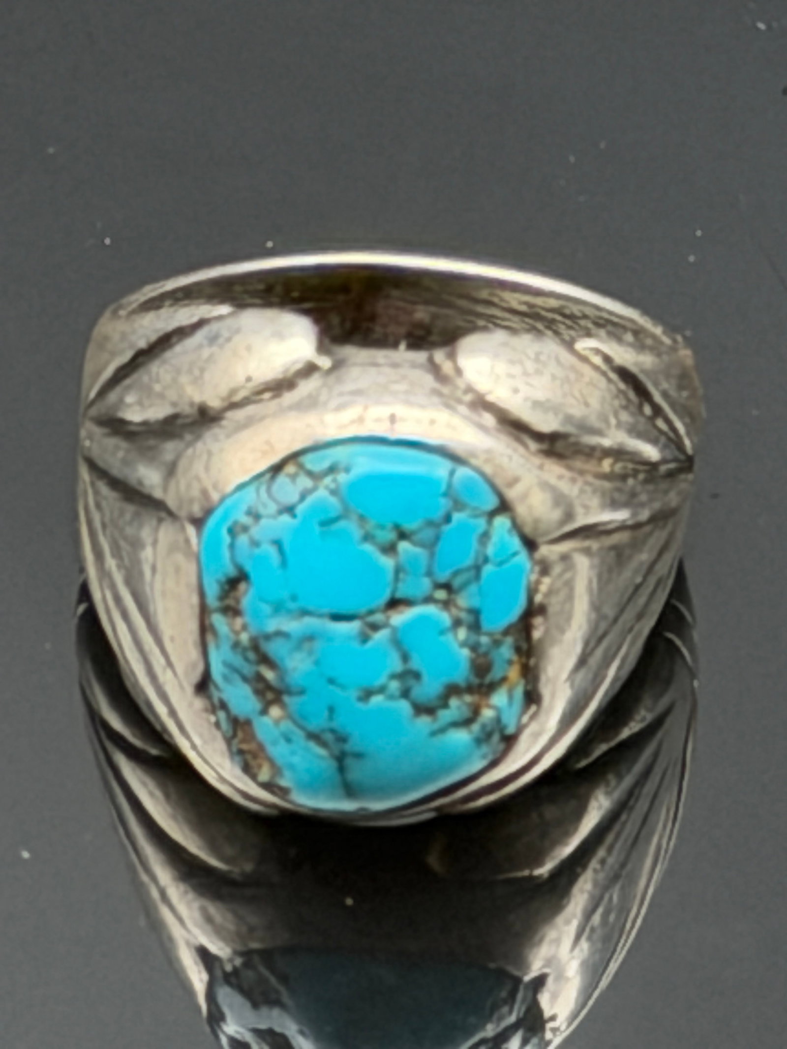 15g-Vintage Sterling Silver Turquoise Statement Ring: Vintage sterling silver ring featuring a natural turquoise cabochon with attractive dark matrix veining. The ring has a bold Southwestern-inspired design with hand-crafted details surrounding the ston