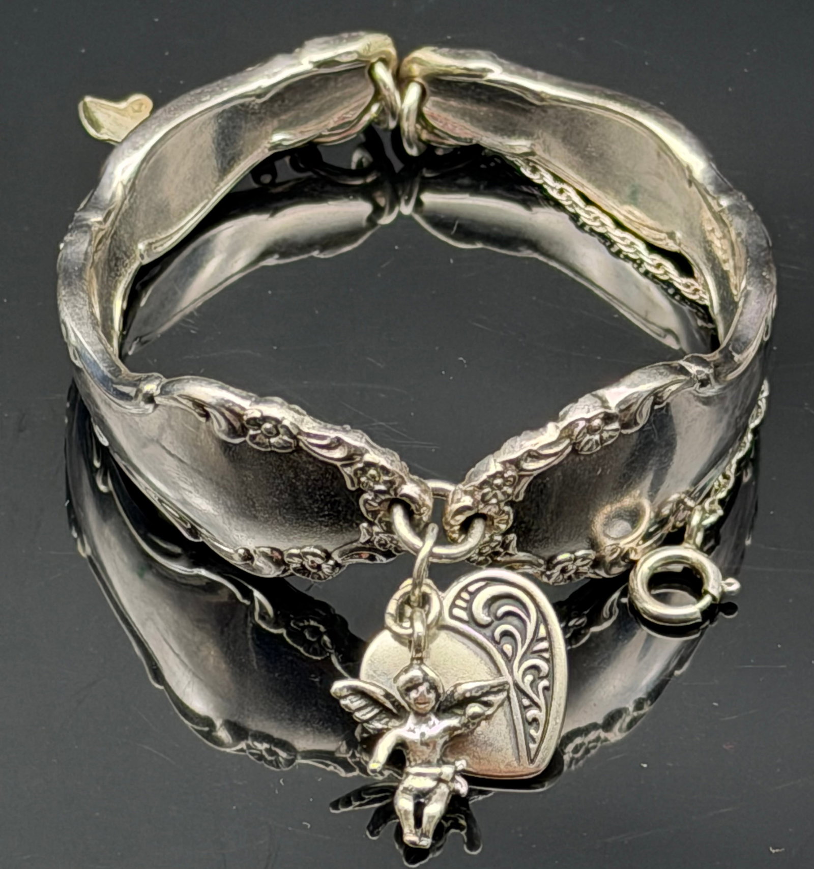 48g-Vintage 925 Sterling Silver Spoon Bracelet Cherub Cupid Heart Charm: Heavy vintage sterling silver spoon bracelet featuring ornate floral detailing and dangling cherub (Cupid) and heart charms. Crafted from sterling silver and marked 925, this unique bracelet showcases