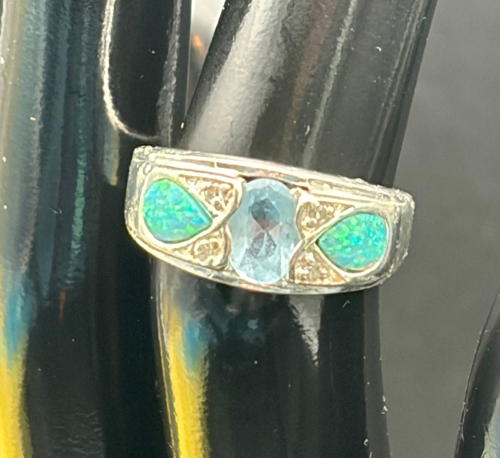 3.8g 925 Silver Blue Topaz Opal Accent Ring Sz: Sterling silver ring stamped 925, featuring an oval light blue topaz center stone accented by two vibrant opal inlays and small clear accent stones. Weighs 3.8 grams. Elegant statement design with att