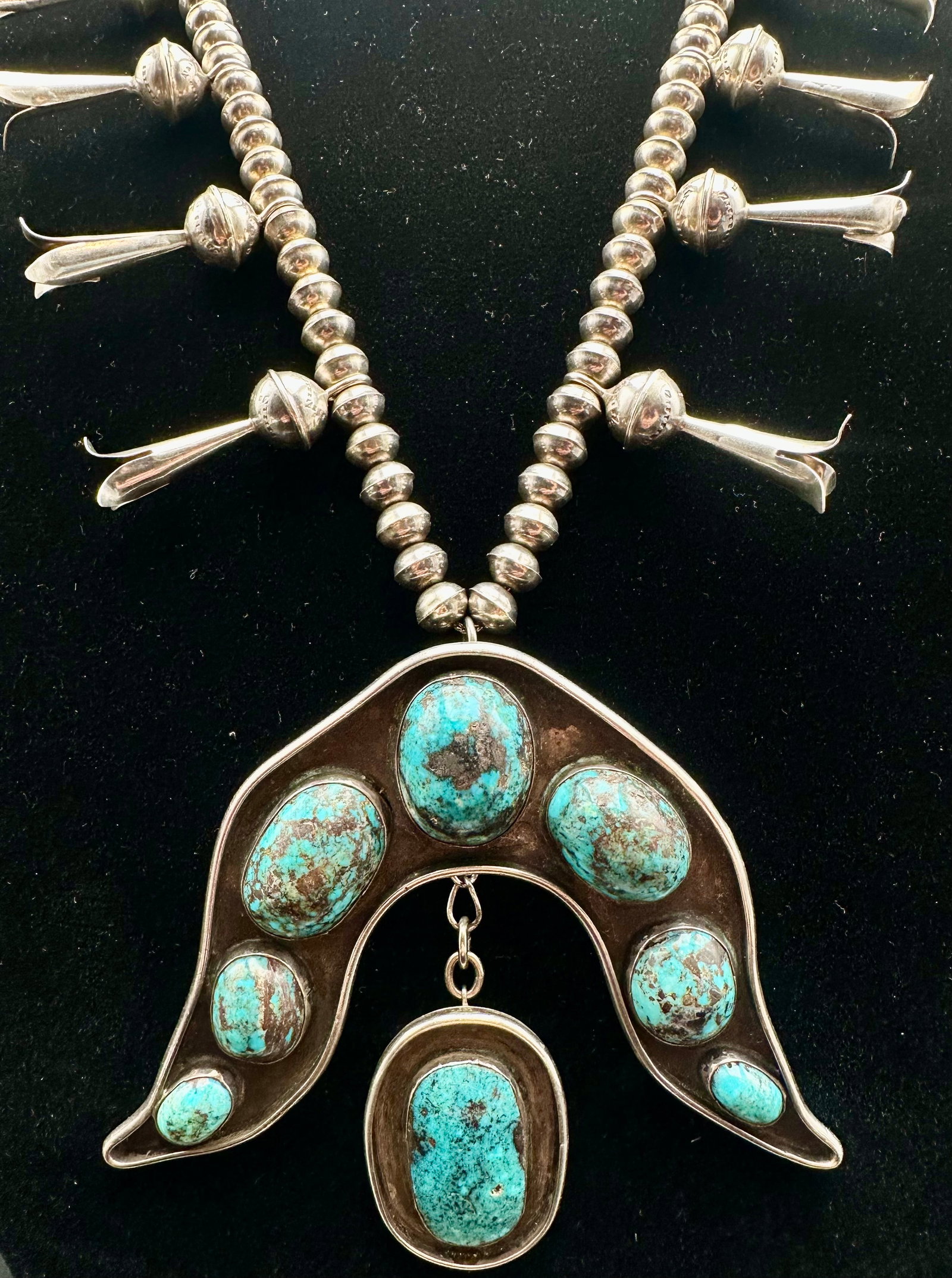 Vintage Navajo Turquoise Squash Blossom Necklace Sterling Silver 190g: Vintage Native American Navajo squash blossom necklace featuring hand-fabricated sterling silver Navajo pearl beads and a traditional naja pendant set with natural turquoise stones. The necklace displ