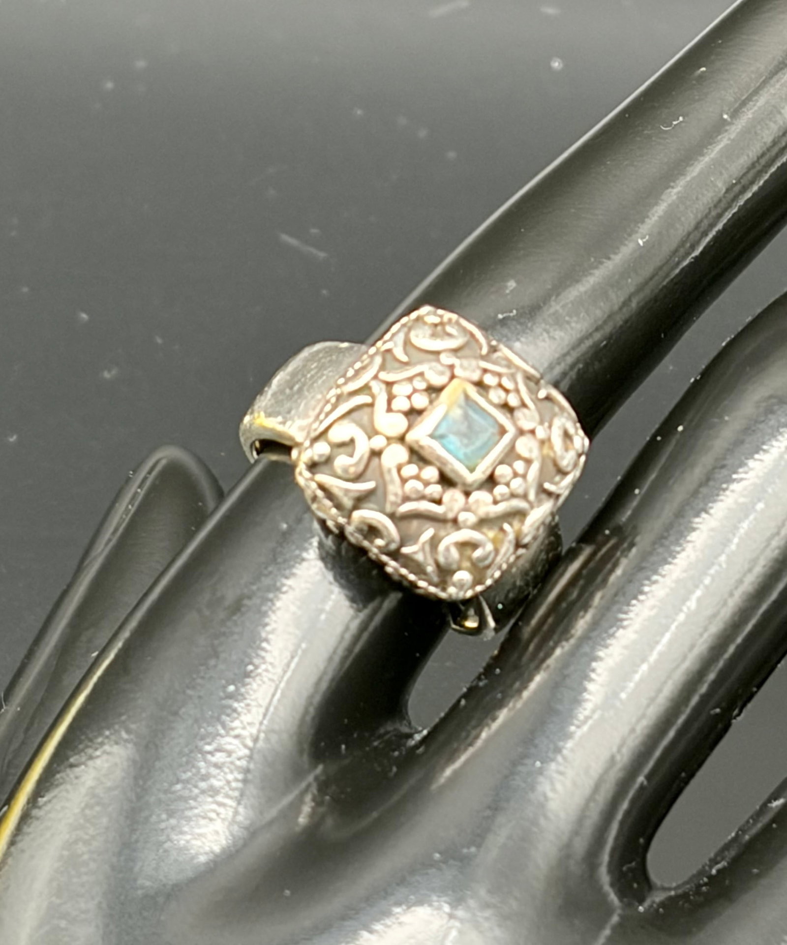 11.0g 925 Silver Aquamarine Filigree Ring: Vintage 925 sterling silver ring weighing 11.0g, featuring a square-cut pale blue gemstone set within an ornate filigree-style design. The detailed floral and scrollwork pattern gives the ring an eleg