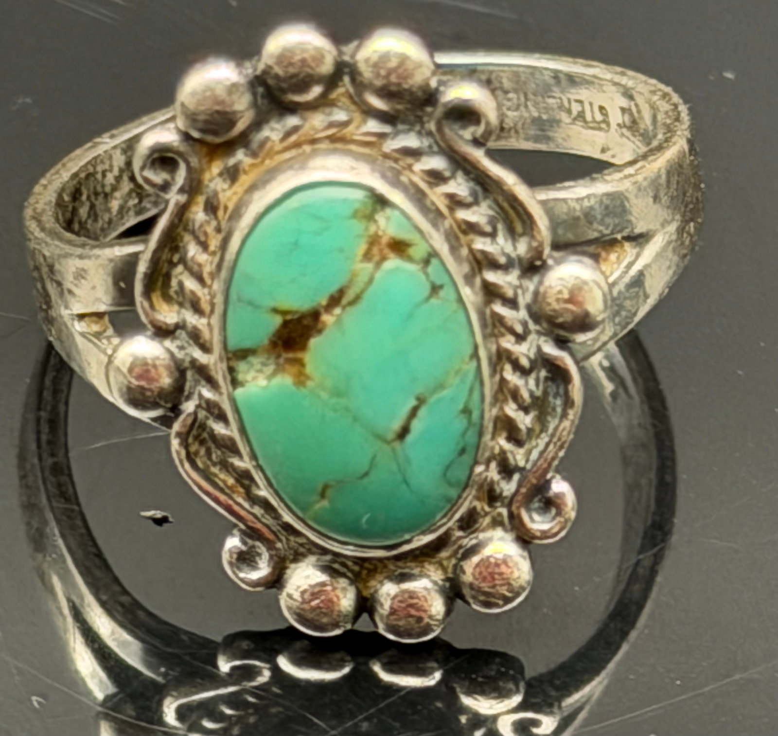 4g-Vintage Sterling Silver Turquoise Ring Southwestern Beaded Rope Design: Vintage sterling silver ring featuring an oval turquoise stone with natural brown matrix. The ring has a classic Southwestern-inspired design with twisted rope and bead accents surrounding the stone. 