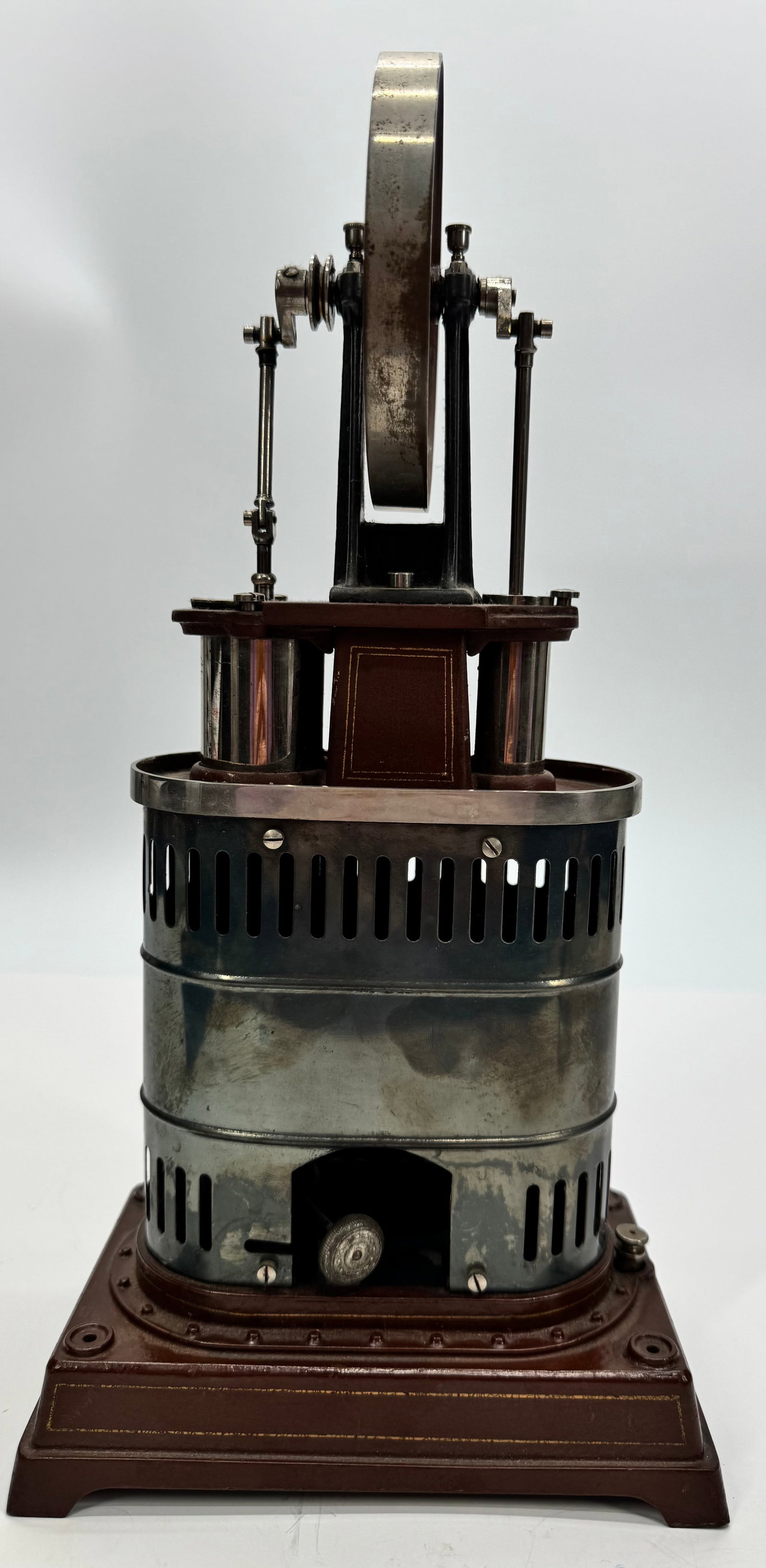 J. Falk Hot Air Engine Scientific Demonstration Model: Antique J. Falk hot air engine model featuring a large flywheel, twin-cylinder configuration, and integrated spirit-lamp style heater mounted on a decorative wood base. Designed as an educational and 