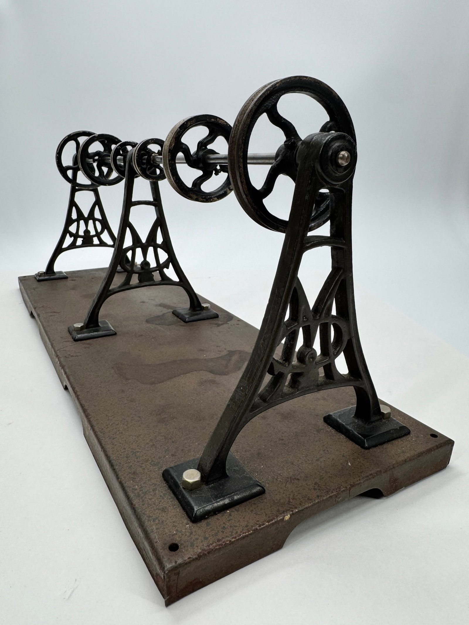 Antique Märklin Line Shaft Transmission Model: Antique Märklin cast iron line shaft transmission model featuring multiple pulleys mounted on a steel shaft with ornate cast iron supports and original metal base. Designed as an accessory for Märkl