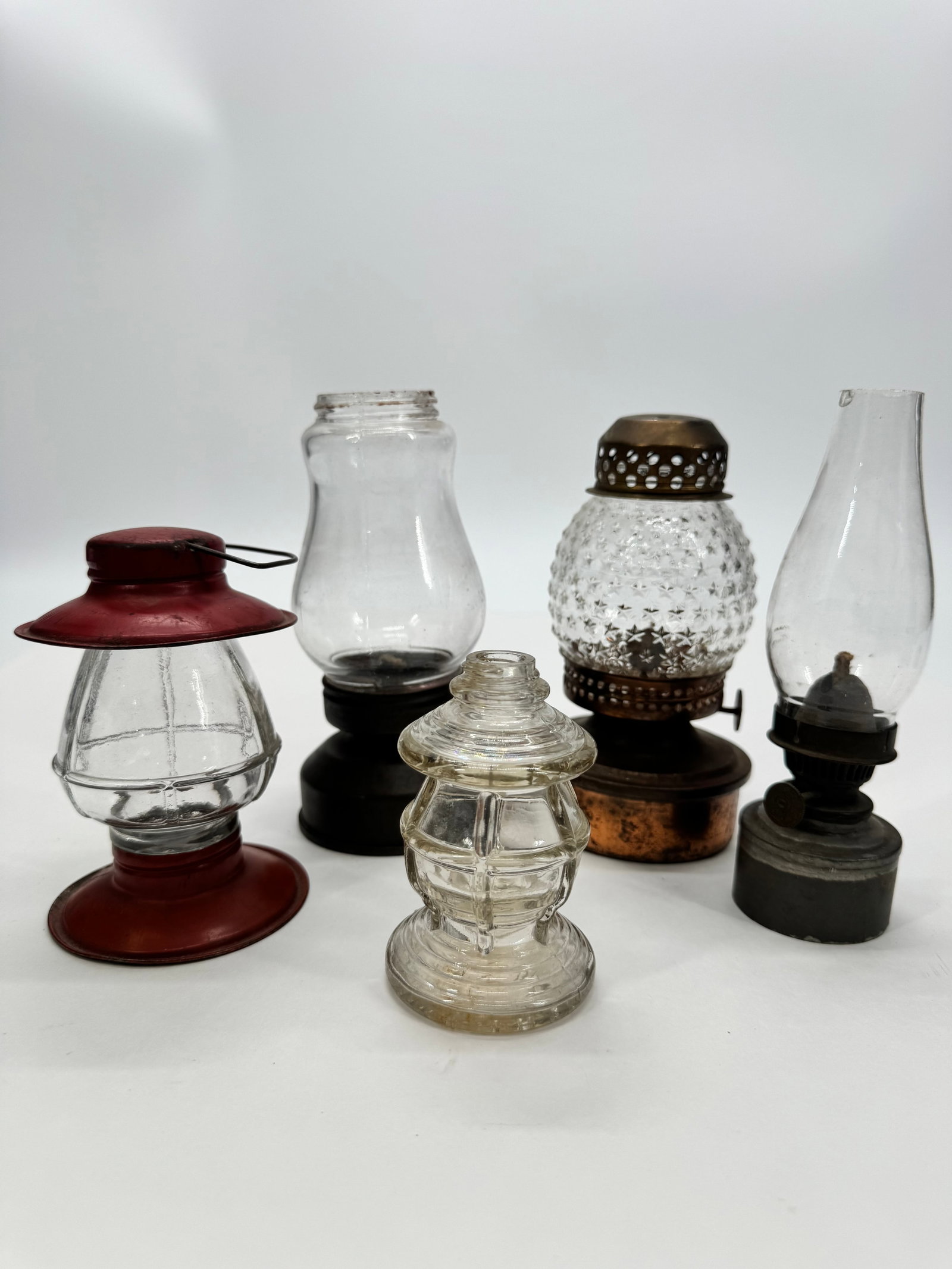 Lot of 5 Vintage Miniature Oil Lamps & Lanterns: Collection of five vintage miniature oil lamps and lanterns in assorted styles and materials. Includes red-painted metal lantern, clear glass lantern, hobnail-pattern glass lamp with brass-tone fittin