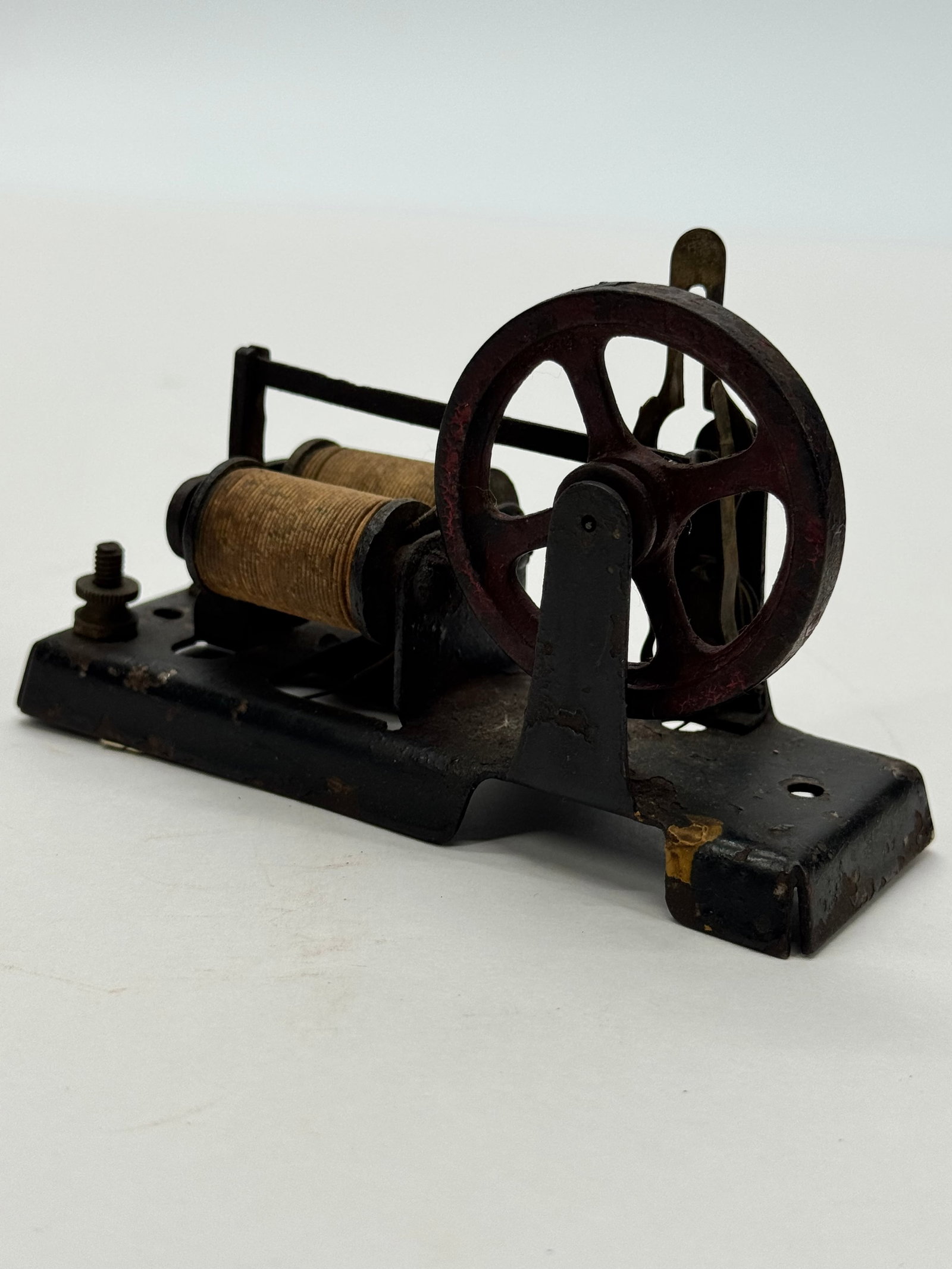 Antique Cast Iron Electric Motor Demonstrator: Antique early 20th-century electromagnetic motor or scientific demonstration apparatus featuring a cast iron base, dual wire-wound field coils, flywheel, and mechanical interrupter assembly. Construct