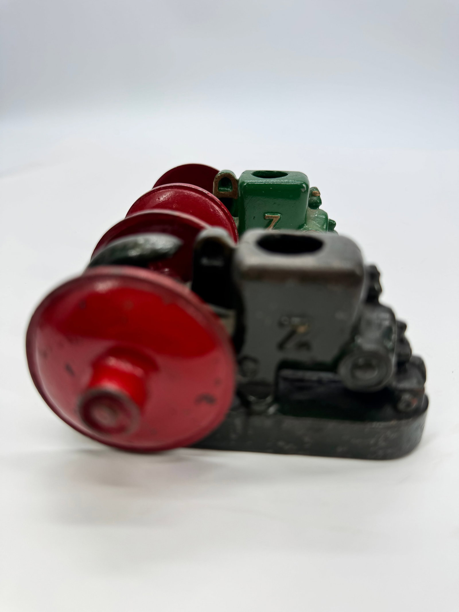 Vintage Cast Iron Model Steam Engine Cylinder Assembly: Vintage cast iron model steam engine cylinder assembly featuring twin red flywheels and green-painted cylinder marked with a raised “Z.” Constructed of heavy cast iron with original painted fi