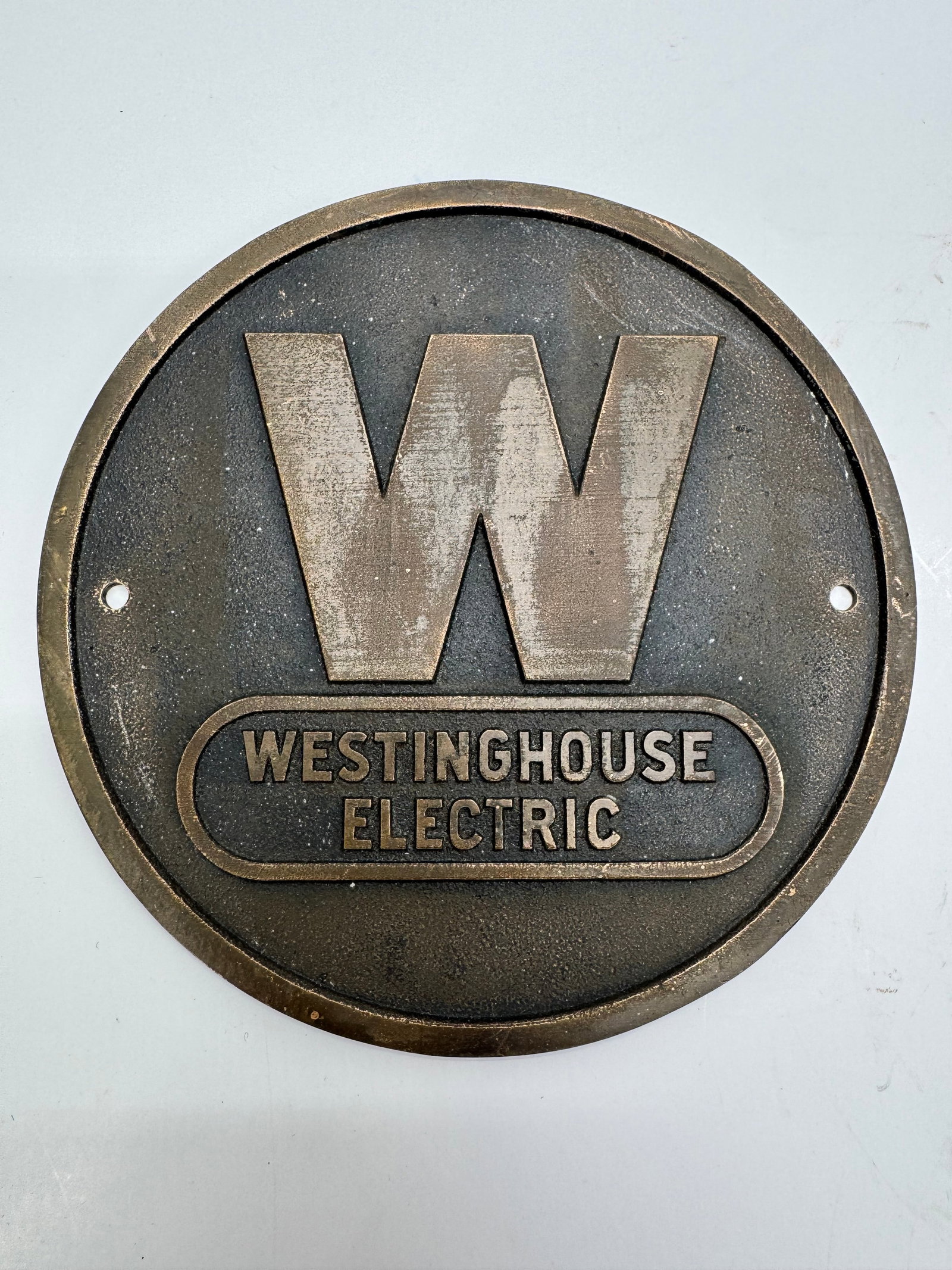 Original Westinghouse Electric Cast Metal Industrial Sign No. 1068854: Original vintage Westinghouse Electric cast metal advertising plaque featuring the iconic raised “W” logo above the WESTINGHOUSE ELECTRIC name. Measures approximately 6 inches in diameter and 