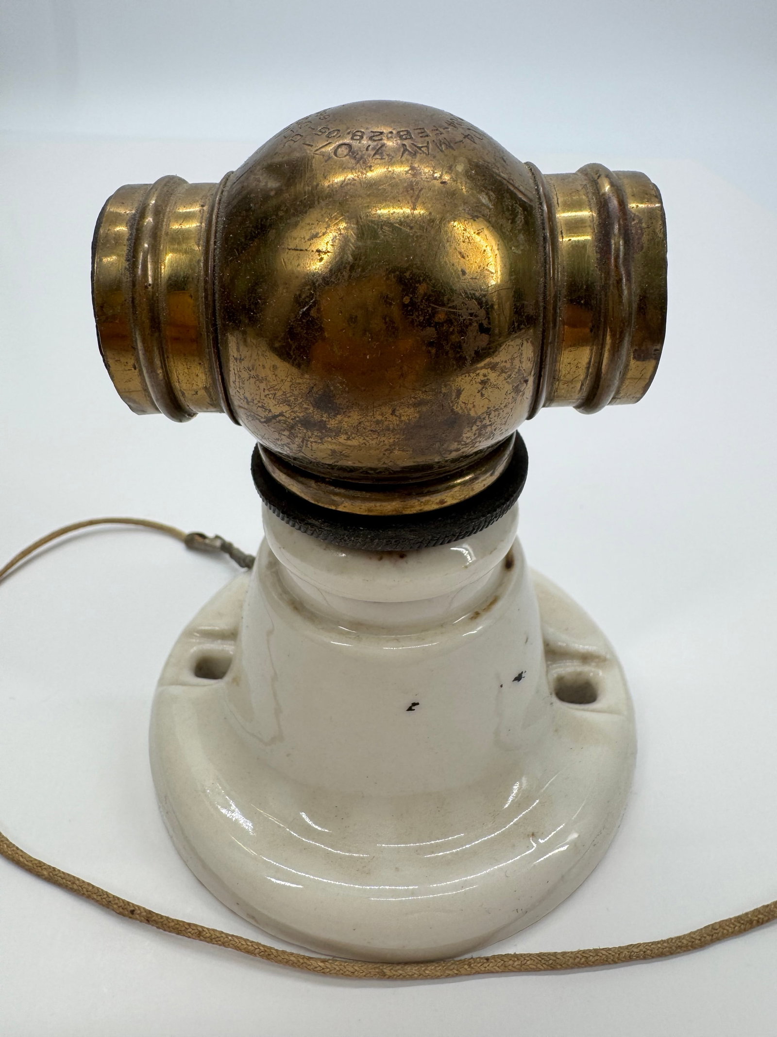 Antique Hubbell Brass & Porcelain Adjustable Wall Sconce Fixture Pat. 1904–1907: Antique Hubbell wall-mounted light fixture featuring a glazed porcelain base with solid brass adjustable ball joint. The brass fitting is embossed with multiple Hubbell patent dates (1904–1907). Ret