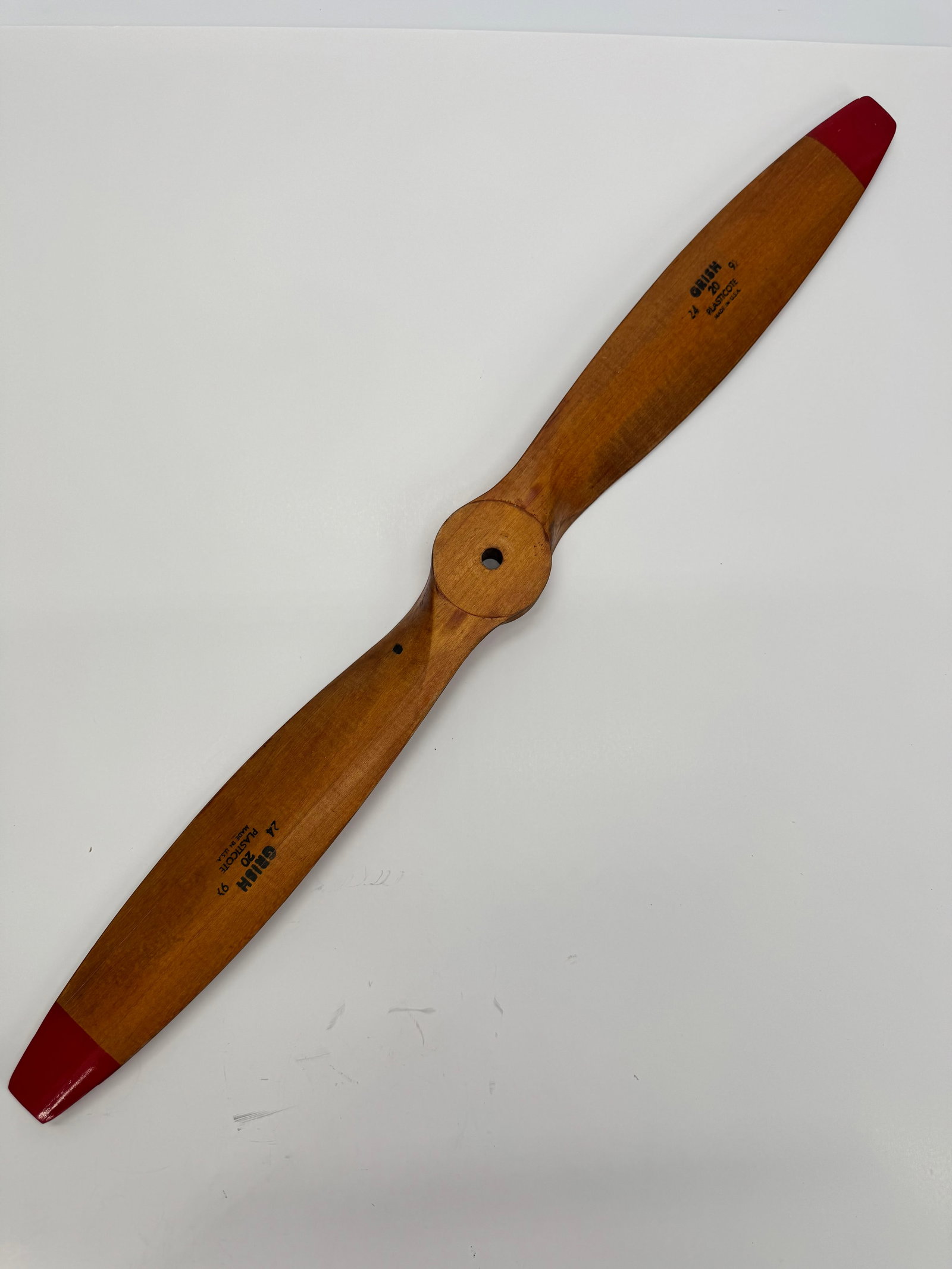 Vintage Grish 24x9 Plasticoat Wooden Model Airplane Propeller USA: Vintage Grish No. 20 “Plasticoat” wooden model airplane propeller marked 24 × 9, Made in U.S.A. Features laminated wood construction with original red safety tips and center mounting hub. A c