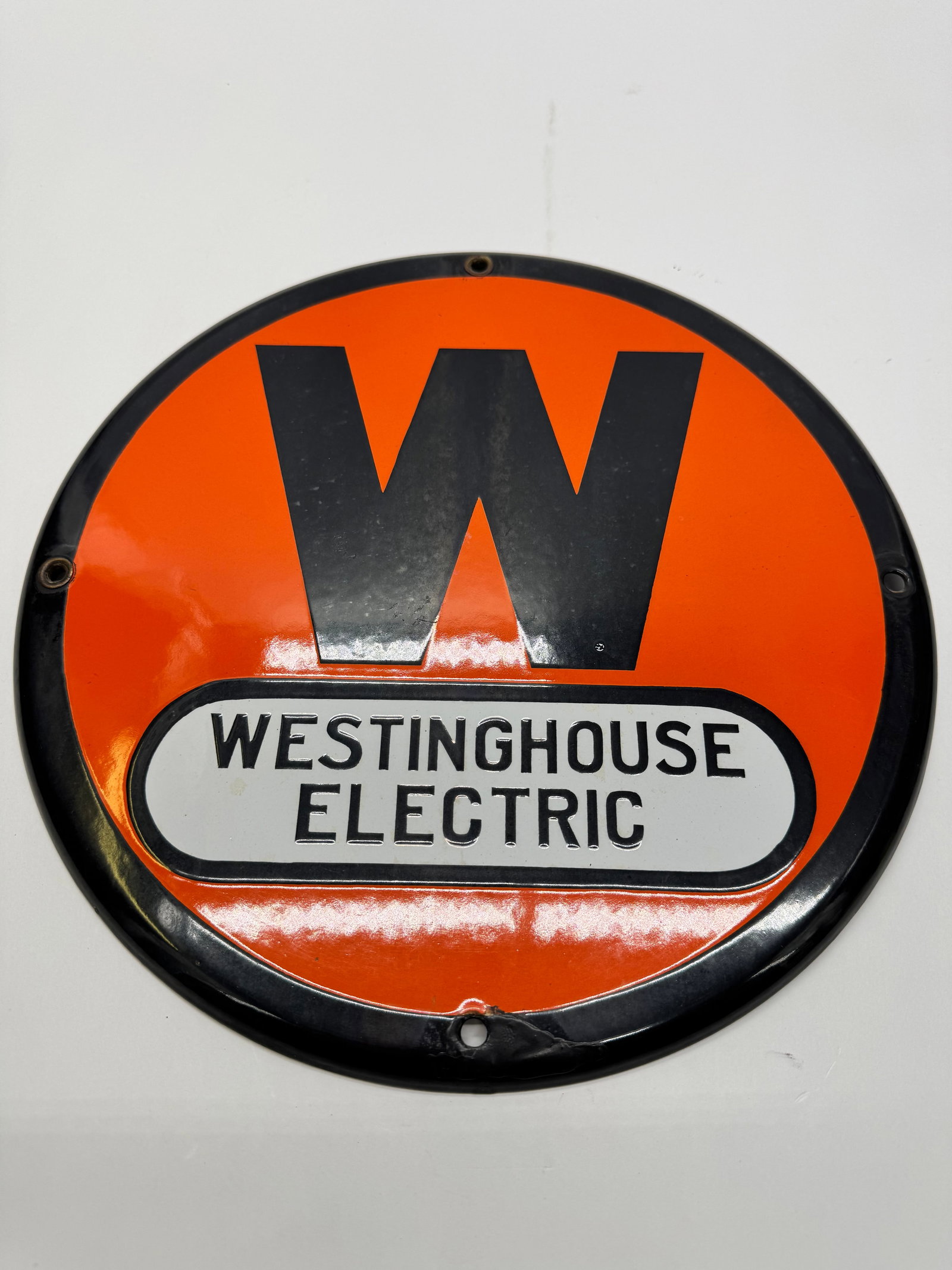 Vintage Westinghouse Electric Porcelain Enamel Dealer Sign: Vintage Westinghouse Electric porcelain enamel advertising sign featuring the iconic orange-and-black “W” logo with raised white Westinghouse Electric panel. Approx. 12” diameter. Displa