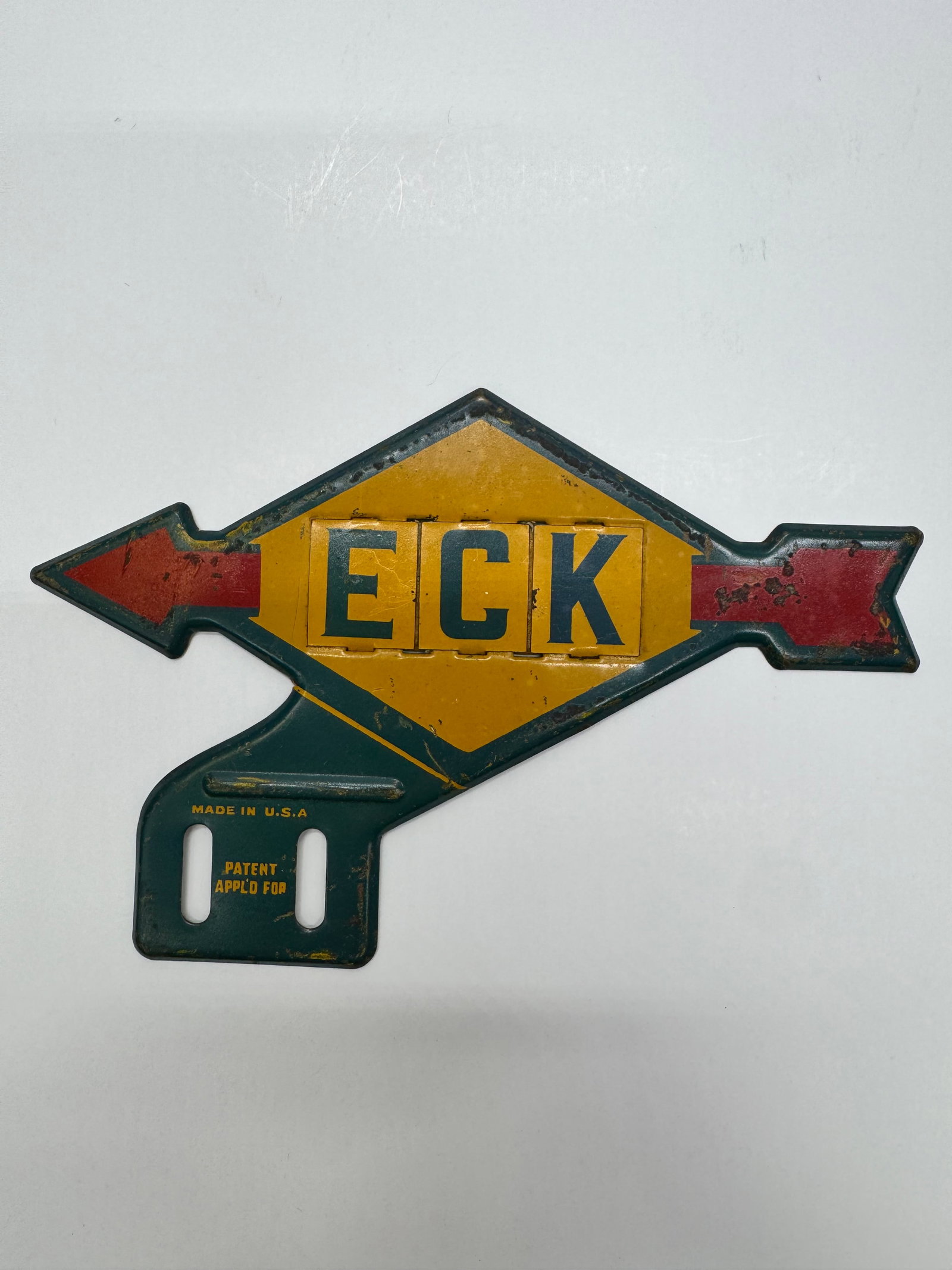 Vintage ECK Embossed Steel License Plate Topper Sign: Original ECK embossed steel automobile license plate topper featuring red directional arrows and yellow center panels spelling “ECK.” Marked “Made in U.S.A.” and “Patent Applied For.