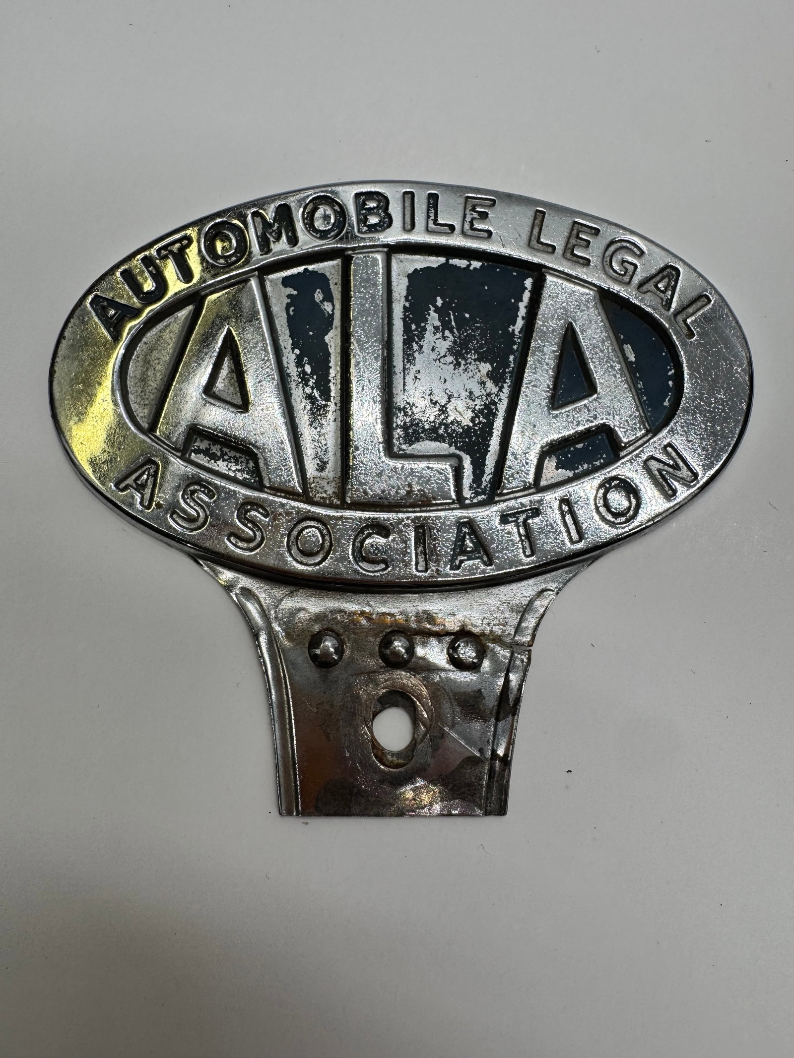 Vintage ALA Automobile Legal Association Radiator Badge: Original Automobile Legal Association (ALA) radiator badge featuring chrome finish with blue enamel accents and original mounting bracket. Dates to the 1920s–1930s and exhibits expected age-related 
