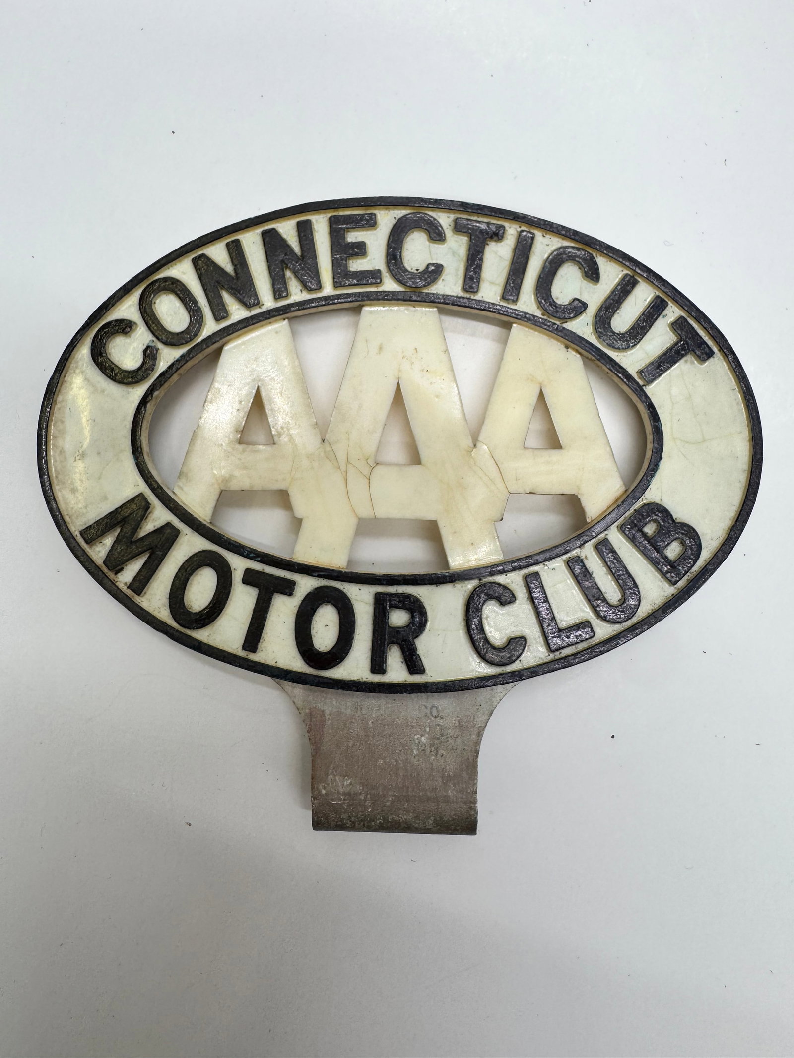 Vintage AAA Connecticut Motor Club Radiator Badge: Original AAA Connecticut Motor Club radiator badge dating to the 1920s–1930s. Nickel-plated metal construction with cream-colored insert and original mounting clamp. Exhibits age-related crazing and