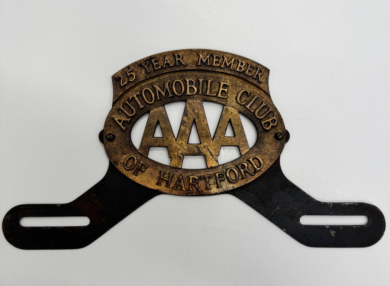 Vintage AAA Hartford 25 Year Member Radiator Badge: Rare Automobile Club of Hartford AAA 25 Year Member radiator badge in cast brass with original black mounting bracket. Features attractive aged patina and honest wear from age and use. A desirable pie