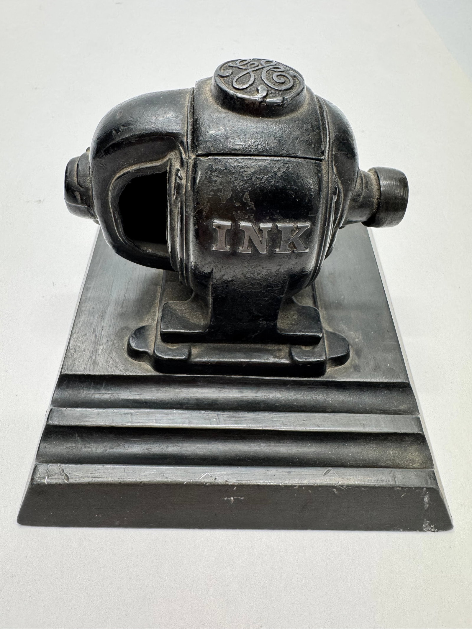 Antique GE General Electric Cast Iron Motor Inkwell Desk Accessory: Antique General Electric cast iron motor-form inkwell with raised GE logo and “INK” cast into the housing. Early industrial desk accessory designed to hold a removable glass ink bottle. Missin