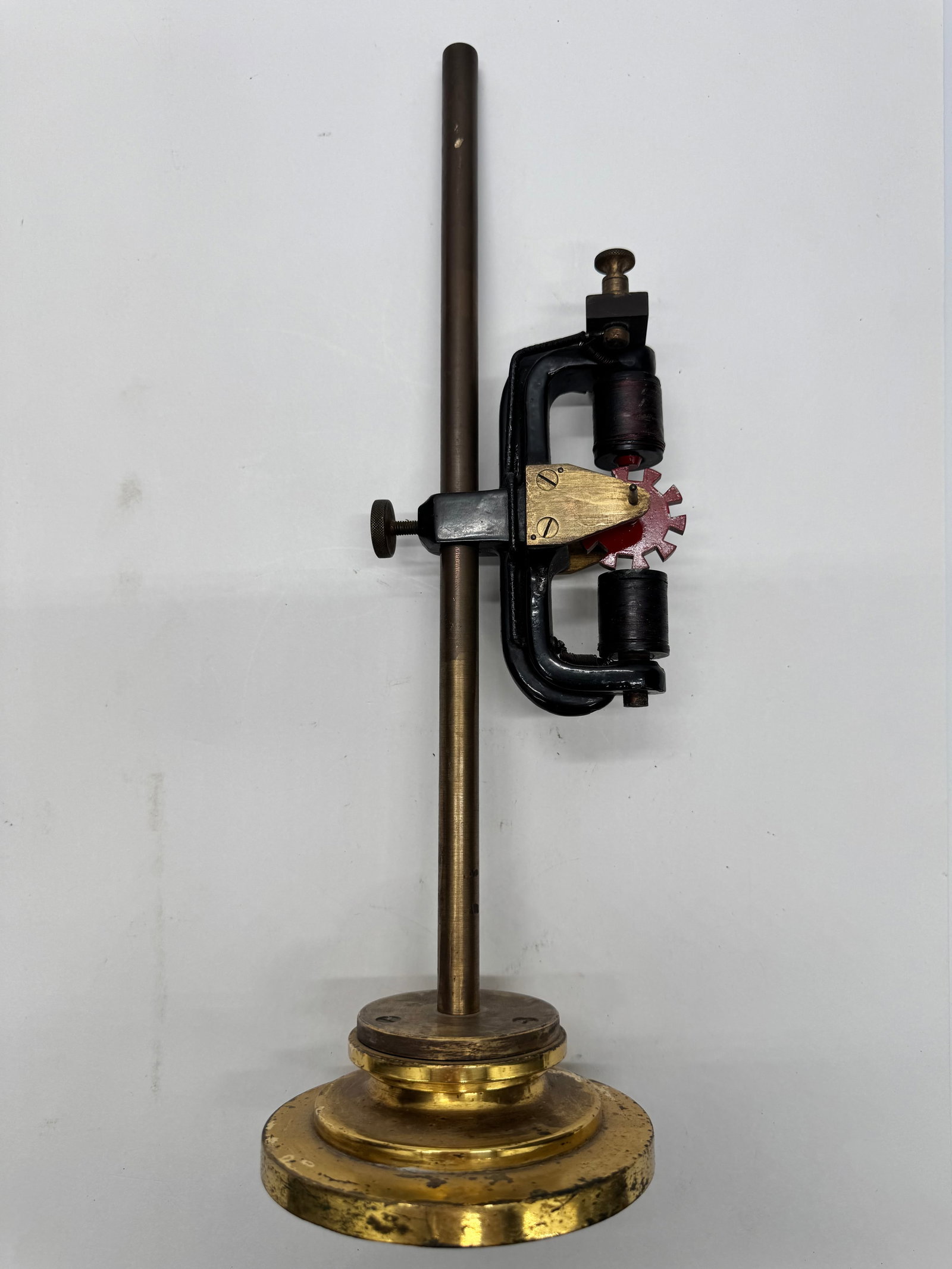 Antique Electromagnetic Physics Demonstration Apparatus: Antique educational electromagnetic demonstration device featuring dual wire-wound coils, brass fittings, and rotating armature wheel. Mounted on an adjustable clamp stand for laboratory or classroom 