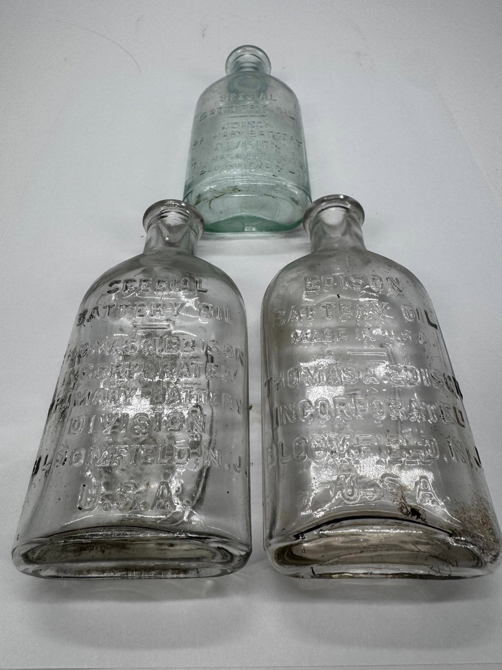 Lot 3 Antique Edison & Johnson Battery Oil Embossed Glass Bottles: Lot of three antique embossed glass battery oil bottles, including one Thomas A. Edison Special Battery Oil bottle and two Johnson & Johnson Special Battery Oil bottles from the Storage Battery Divisi