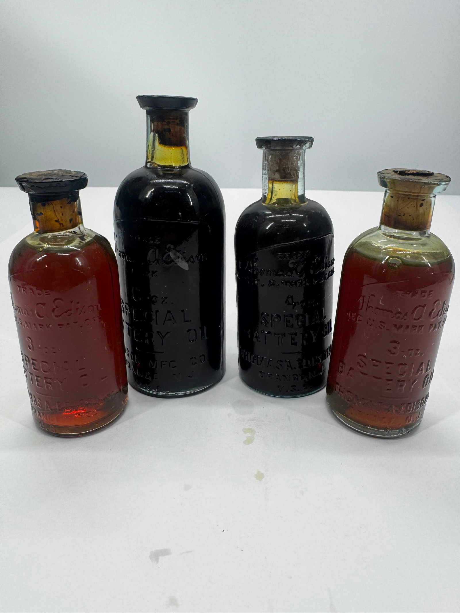 Lot of 4 Antique Thomas A. Edison Special Battery Oil Embossed Glass Bottles: Lot of four antique embossed Thomas A. Edison Special Battery Oil glass bottles in assorted sizes, including 3 oz., 4 oz., and the desirable 6 oz. examples. Manufactured by Thomas A. Edison, Inc., Ora