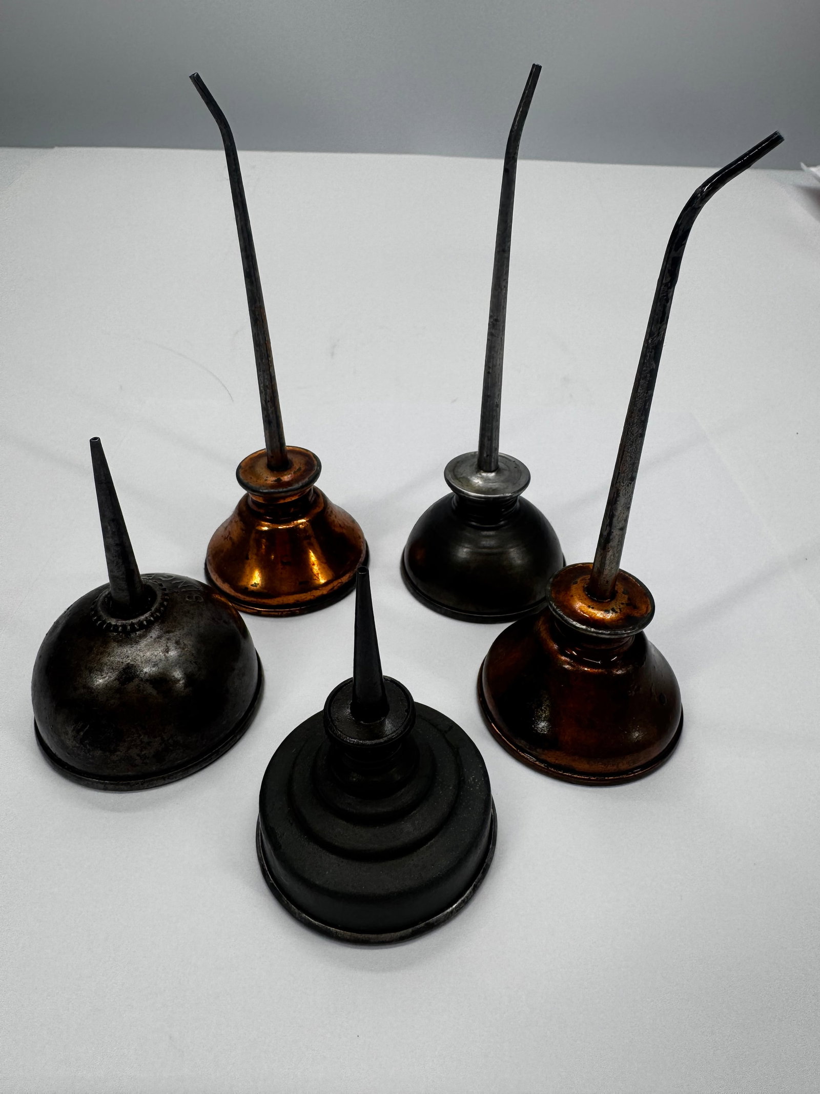 Lot of 5 Vintage Metal Oil Cans & Pump Oilers Assorted Sizes: Lot of five vintage metal oil cans and pump oilers in assorted sizes and finishes, including copper-tone and black examples with fixed spouts. These classic oilers were used for lubricating machinery,
