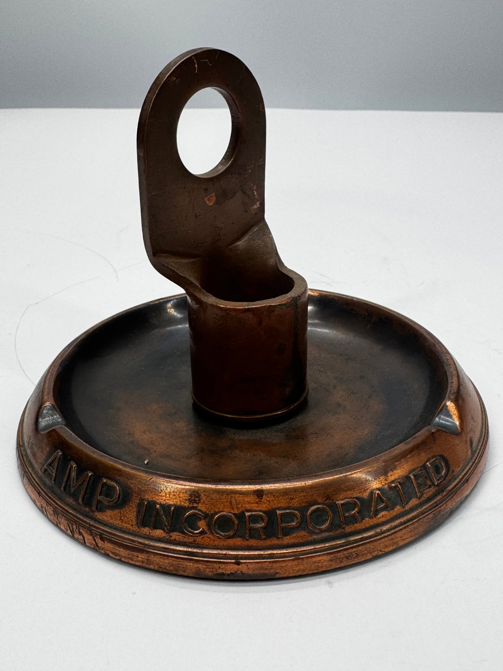 Vintage AMP Incorporated Bronze Advertising Ashtray Salesman Sample: Vintage AMP Incorporated cast bronze advertising ashtray or promotional desk tray featuring a raised electrical terminal or cable lug design at the center. Marked “AMP INCORPORATED” around the