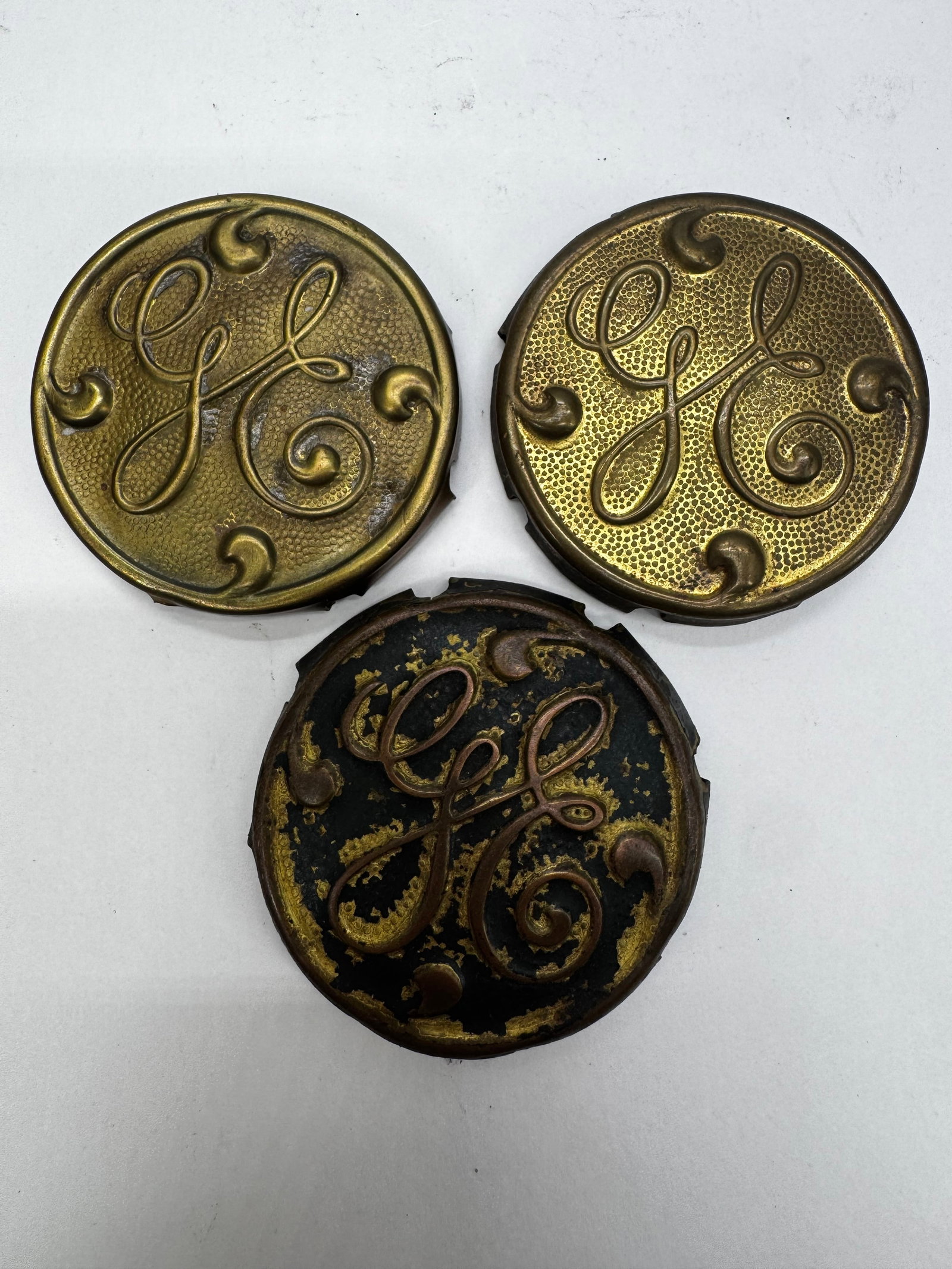 Lot of 3 Antique GE General Electric Script Fan Medallions: Lot of three vintage General Electric (GE) script logo medallions, originally used as cage badges on antique GE electric fans. Cast brass or bronze construction with original aged patina and finish. A