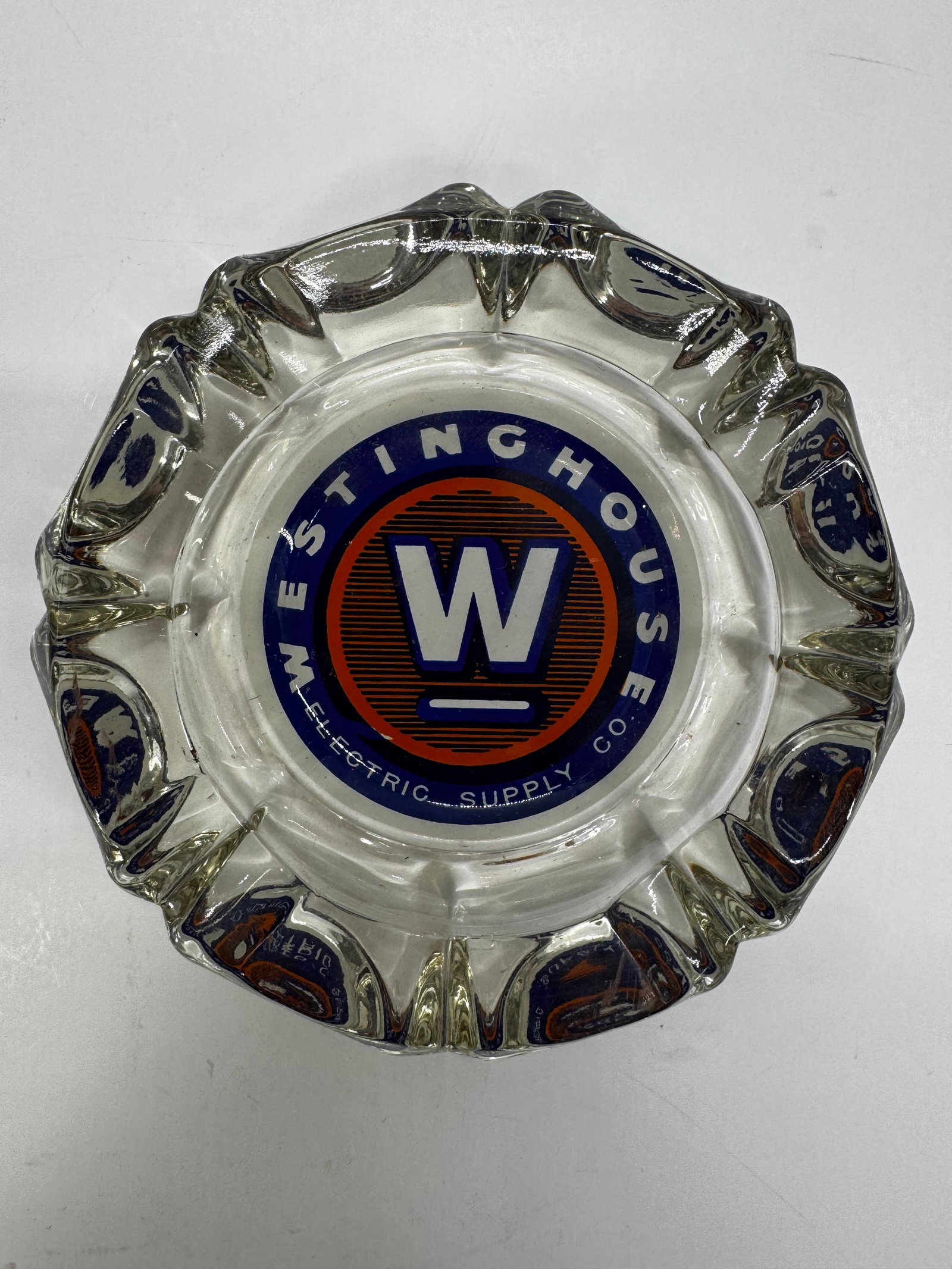 Vintage Westinghouse Electric Supply Co. Glass Advertising Ashtray: Vintage Westinghouse Electric Supply Co. advertising ashtray made of clear molded glass, dating to the 1950s–1960s. Features a colorful reverse-painted Westinghouse logo with the iconic white “W&r