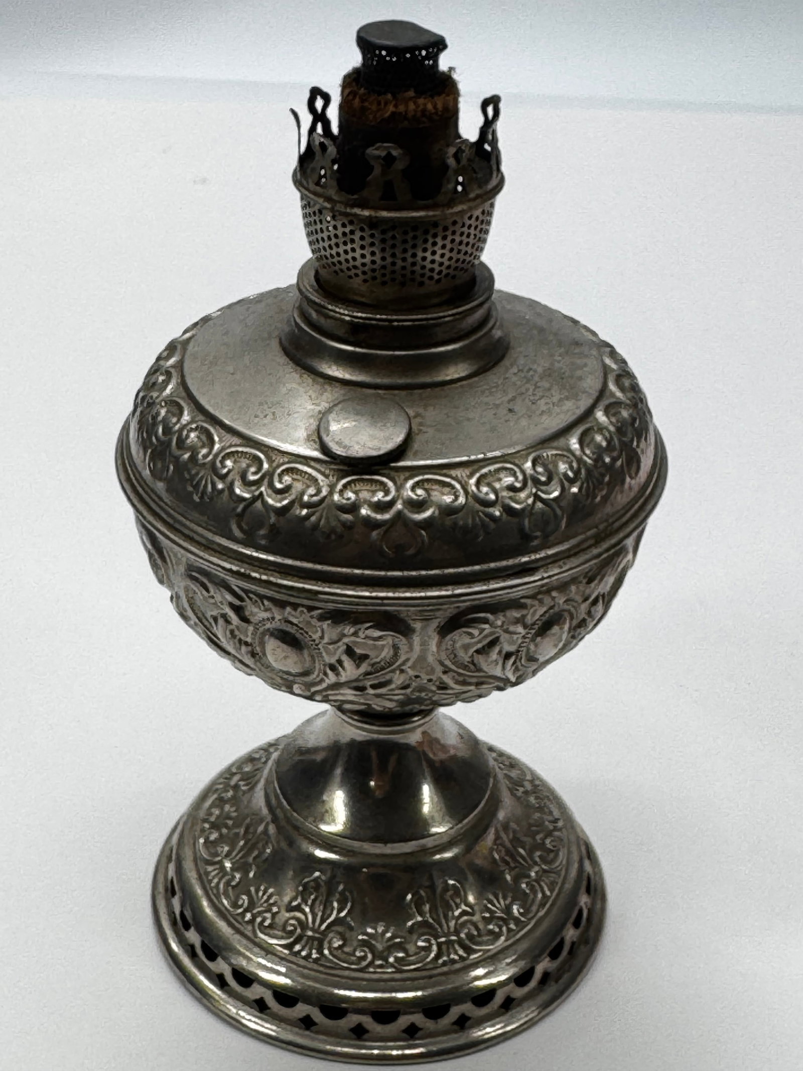 Antique Silver Plate Oil Lamp Base w/ Lev-A Burner: Antique silver-plated kerosene oil lamp base featuring an ornate embossed floral design and fitted with a Lev-A center-draft burner. The burner wick adjustment knob is marked LEV-A. Missing the glass 