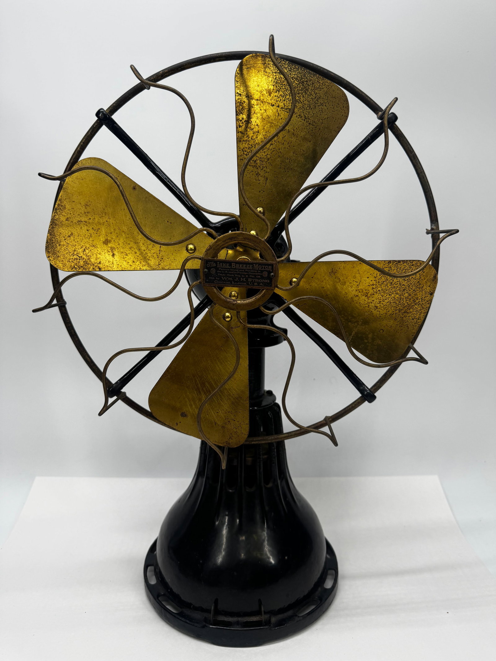 Antique Lake Breeze Motor Brass Blade Electric Fan by Wm. J.H. Strong Chicago: Antique Lake Breeze Motor electric desk fan manufactured by Wm. J.H. Strong, Chicago, Illinois, dating to the early 1900s (circa 1905–1915). This rare fan features a heavy cast iron base with origin