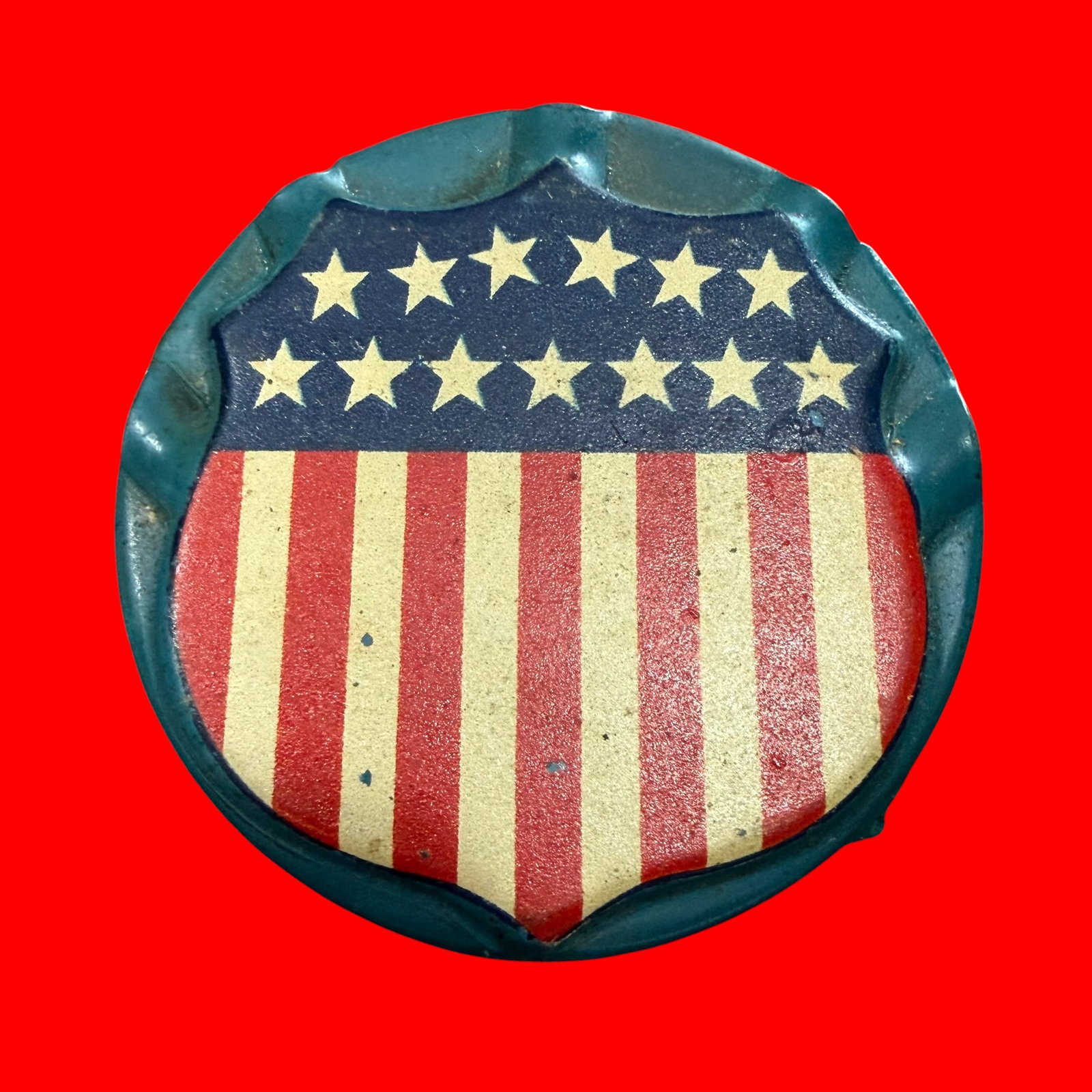 American Flag Shield Flag Holder Radiator Parade Badge: Description: Early 1900s radiator badge for an automobile. Patriotic theme with US flag shield. Meant to hold 5 small flags. Marked Pat Appd For Dettra. / Material: Steel. / Size: 2 5/8” diamete