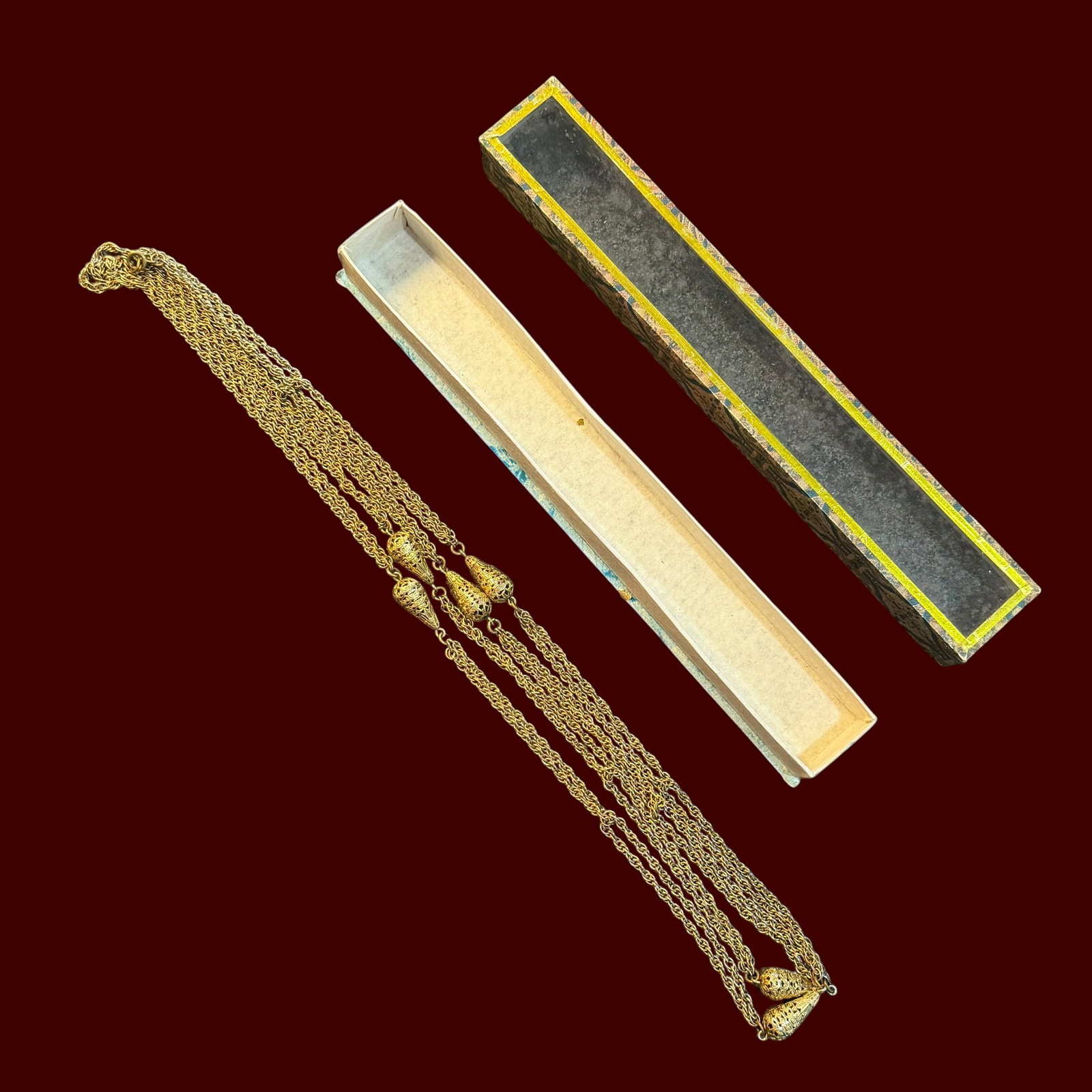 Vintage Gold Tone Asian Style Chain Necklace w/ Souvenir Display Box: Description: Vintage Asian style necklace, gold tone with tear shaped amulets. Comes in souvenir display box. / Material: Gold tone base metal. / Size: 60” long overall. / Condition: Ready to be