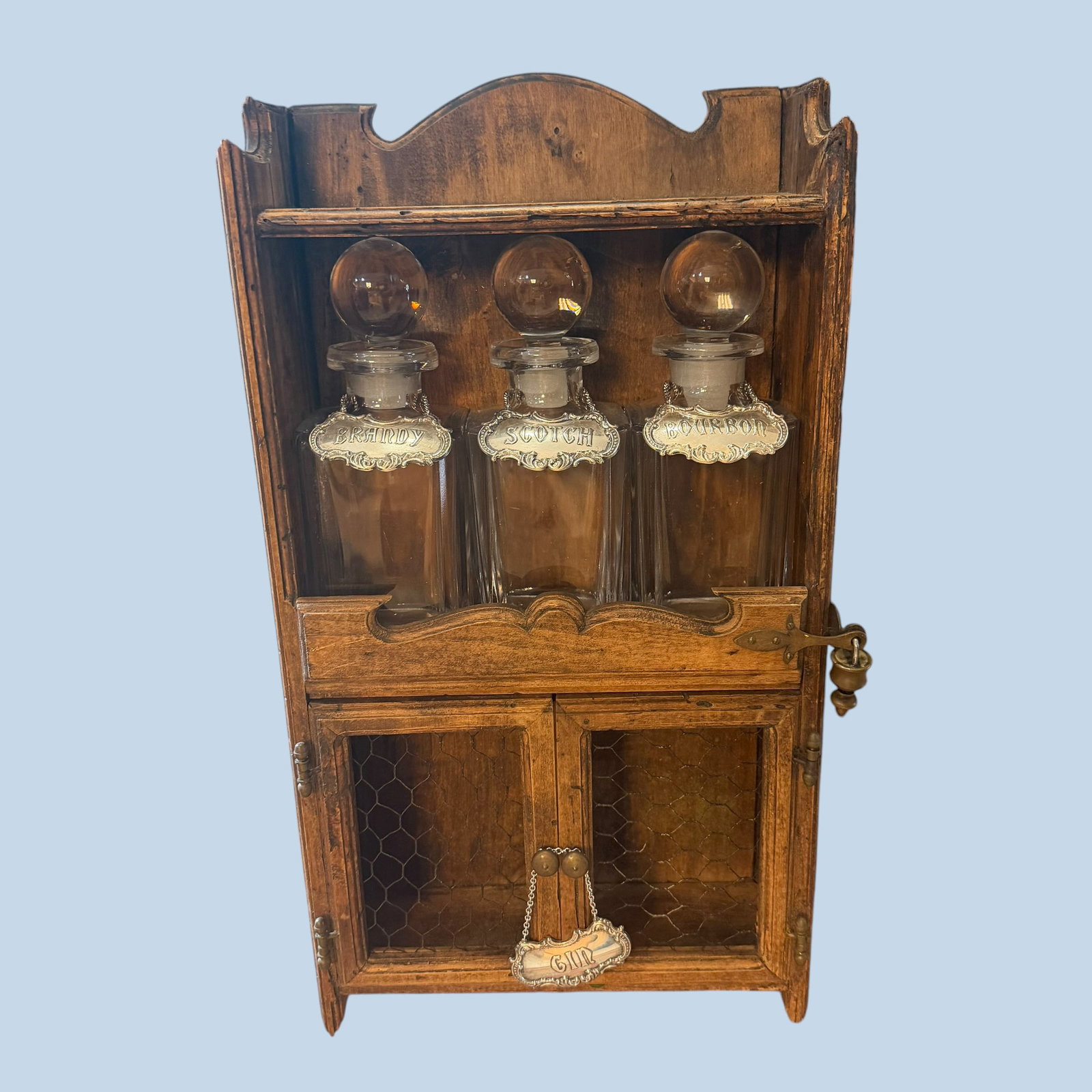 Wood Wall Mount 3 Decanter Liquor Cabinet Sterling Silver Gotham Bourbon Brandy Scotch Gin Tags 57g: Description: Antique wood wall mount liquor cabinet with 3 heavy glass decanters, which lock into place with lock and key shown. Gorham Sterling Silver tags included as shown. Back of cabinet is stamp