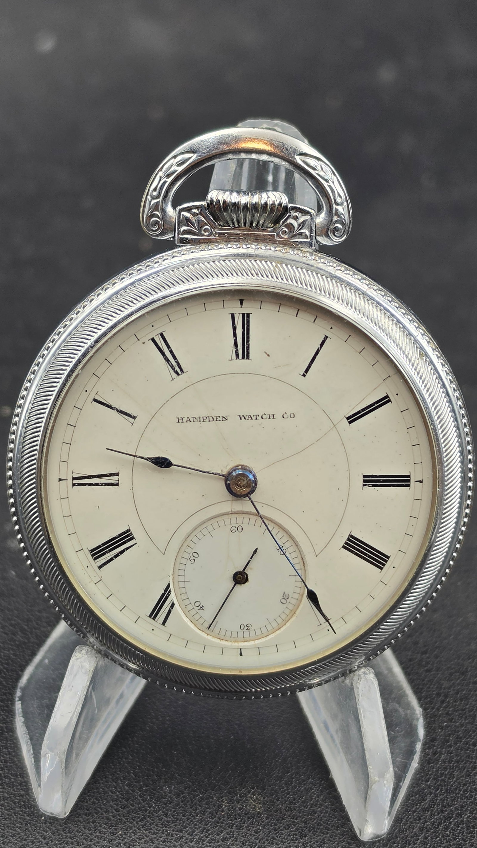 1885 Hampden Watch Co Grade 55 15 Jewel Adjusted 18s Pocket Watch Defiance Silver Case: An antique 1885 Hampden Watch Co. pocket watch from Springfield, Massachusetts, in a Defiance silverode open face case with engine-turned linear engraving on the back cover and a decorative scroll mot