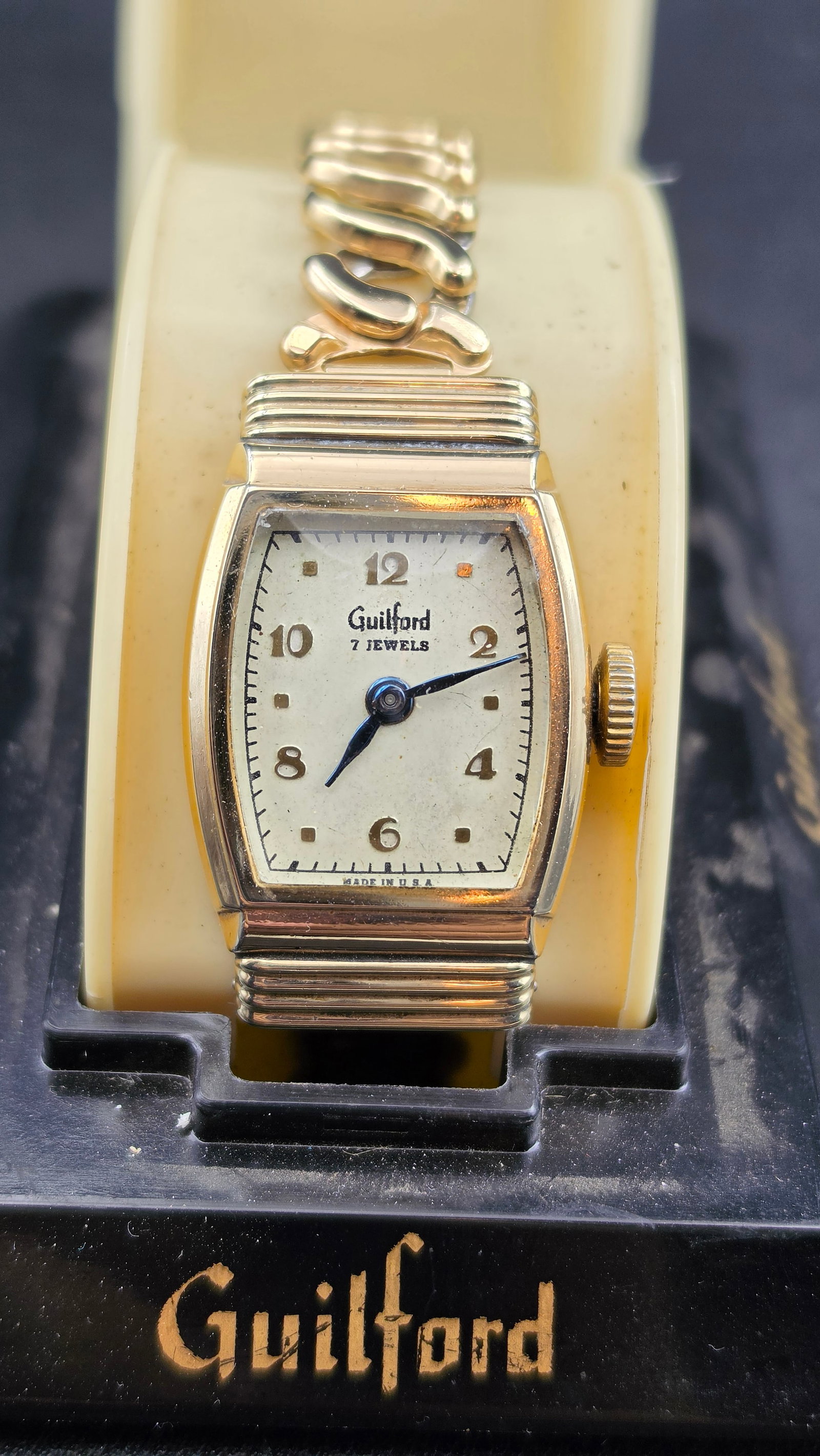 NOS Guilford "Guilford 62" Ladies' 7 Jewel Gold-Filled Watch 1940s Running on Original Store Display: This is a New Old Stock ladies' Guilford wristwatch, 7-jewel manual-wind movement (Guilford 62), tonneau-shaped gold-filled case, running and confirmed on the original ivory "American Made" Guilford s